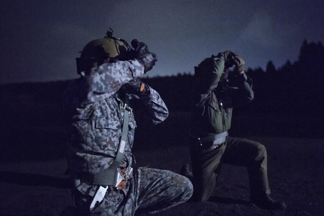 (Left to right) Japan Air Self-Defense Force Tech. Sgt. Shohei Sakane, Komatsu Air Rescue Squadron pararescue jumper, and Tech. Sgt. Yuji Yasutani, Komatsu Air RQS UH-60J flight engineer, protect their gears from the UH-1N Iroquois helicopter rotor wash at a helicopter landing zone at Combined Arms Training Center, Camp Fuji, Japan, Nov. 8, 2016, during the Keen Sword 17. The 459th AS and Komatsu Air RQS conducted a three-day NVGs and hoist familiarization training. (U.S. Air Force photo by Yasuo Osakabe/Released) 