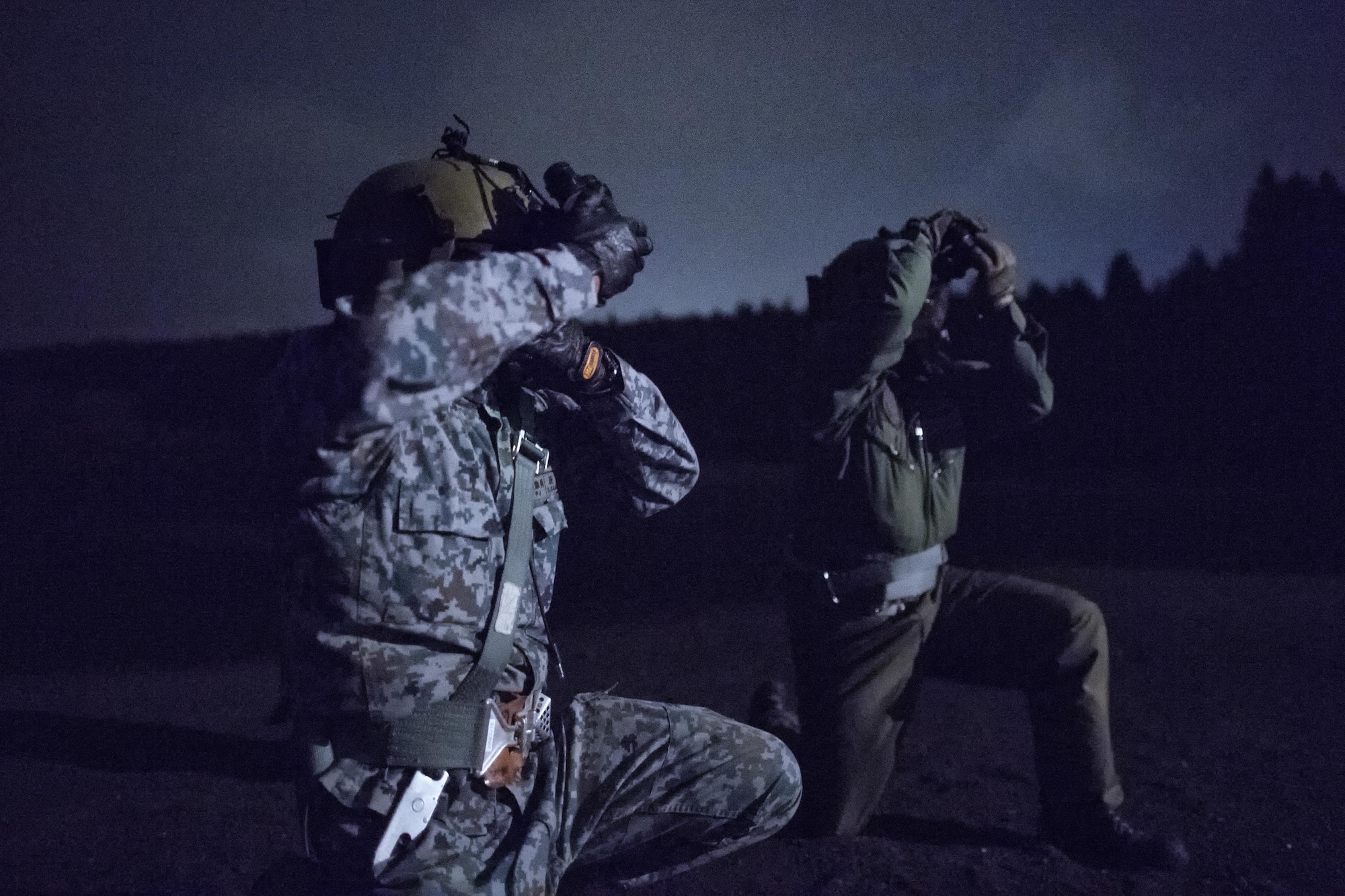(Left to right) Japan Air Self-Defense Force Tech. Sgt. Shohei Sakane, Komatsu Air Rescue Squadron pararescue jumper, and Tech. Sgt. Yuji Yasutani, Komatsu Air RQS UH-60J flight engineer, protect their gears from the UH-1N Iroquois helicopter rotor wash at a helicopter landing zone at Combined Arms Training Center, Camp Fuji, Japan, Nov. 8, 2016, during the Keen Sword 17. The 459th AS and Komatsu Air RQS conducted a three-day NVGs and hoist familiarization training. (U.S. Air Force photo by Yasuo Osakabe/Released) 