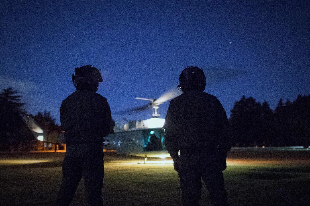 (Right to left) Japan Air Self-Defense Force Maj. Hirotaka Nakamura and Maj. Junichi Okamoto, Komatsu Air Rescue Squadron UH-60J pilots, wait for a U.S. Air Force UH-1N Iroquois takeoff at U.S. Army Sagami General Depot, Nov. 9, 2016, during the Keen Sword 17. The 459th AS and Komatsu Air RQS Airmen conducted a three-day NVGs and hoist familiarization training. (U.S. Air Force photo by Yasuo Osakabe/Released)  