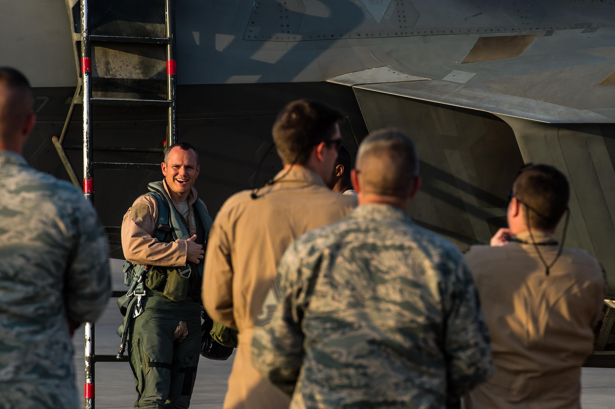 Brig. Gen. Charles Corcoran, 380th Air Expeditionary Wing Commander and F-22 Raptor pilot, laughs as he is congratulated for successfully completing 1000 flight hours in the F-22 at an undisclosed location in Southwest Asia, Nov. 11, 2016. Corcoran is one of 15 F-22 pilots to reach the 1000-flying-hour milestone. (U.S. Air Force photo by Senior Airman Tyler Woodward)
