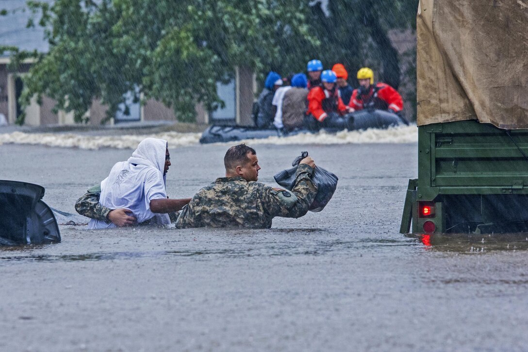 North Carolina Army National Guardsmen carry a resident to safety during evacuation efforts in Fayetteville, N.C., Oct. 08, 2016. Heavy rains from Hurricane Matthew have led to flooding as high as five feet in some areas. Army National Guard photo by Staff Sgt. Jonathan Shaw