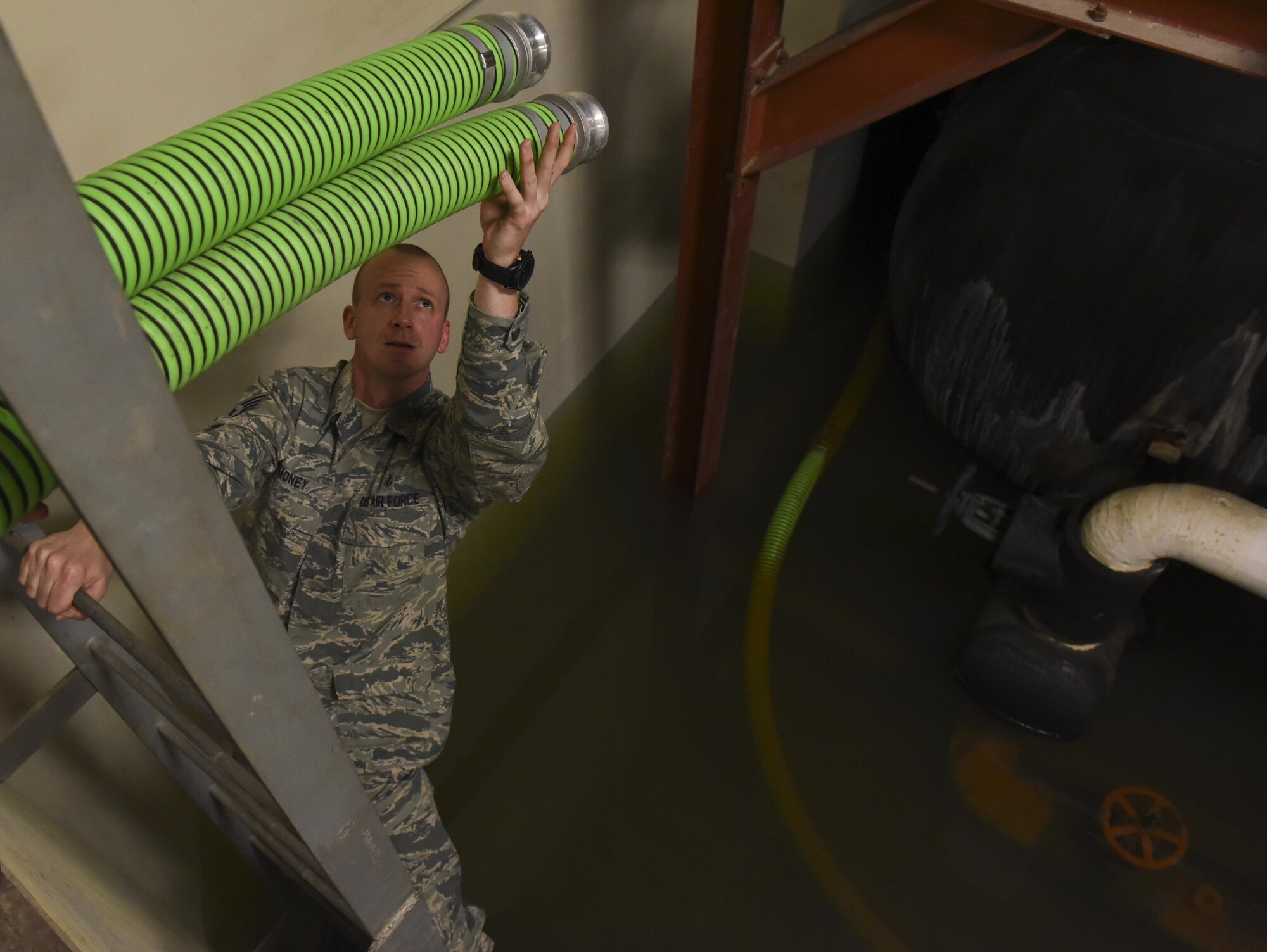 Staff Sgt. Ian Money, 8th Civil Engineering Squadron airmen dormitory leader, lowers a hose into a flooded dormitory basement to discharge water at Kunsan Air Base, Republic of Korea, Nov. 8, 2016. ADLs are responsible for the management of dorm logistics and the wellbeing of occupants who reside in them. (U.S. Air Force photo by Senior Airman Michael Hunsaker/Released)