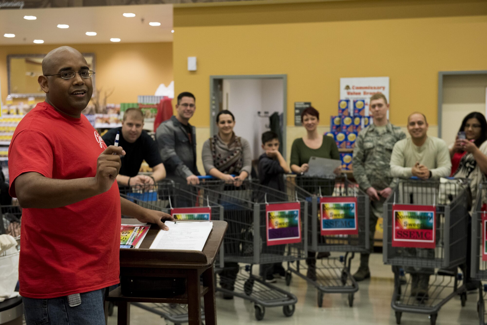 U.S. Air Force Staff Sgt. Willie Moore, left, 52nd Maintenance Squadron propulsion test cell supervisor, explains rules to contestants during the annual Spangdahlem Spouses and Enlisted Members Club Commissary Sweep at Spangdahlem Air Base, Germany, Nov. 15, 2016. During the event, Airmen and families guessed food item prices, answered riddles and shopped against the clock without exceeding their given allowance in order to win various amounts of commissary gift cards. (U.S. Air Force photo by Airman 1st Class Preston Cherry)