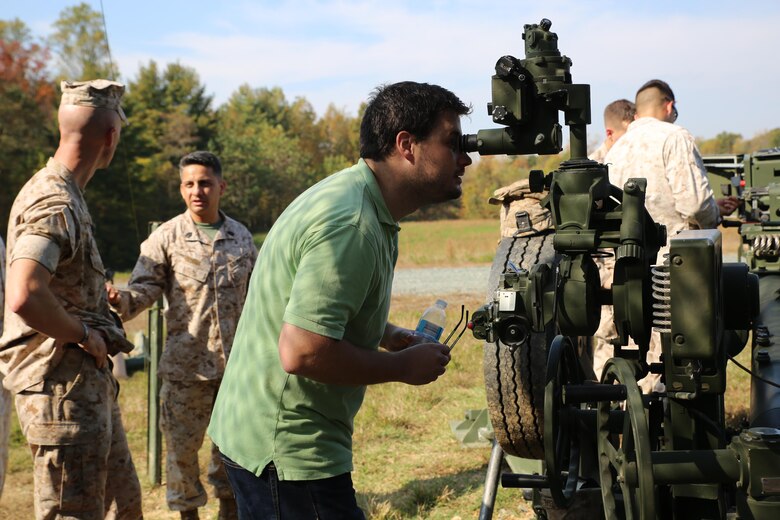 Caleb Hughes, the large-caliber ammunition engineer at MCSC’s Ammunition Program Management Office, looks through a sight used to align the M777 howitzer to a target during a field artillery demonstration at Marine Corps Training Command aboard Marine Corps Base Quantico last month. During the demonstration MCSC employees gained first-hand experience of field artillery Marines in action to inform their work behind the scenes at MCSC. (U.S. Marine Corps photo by Mathuel Browne)