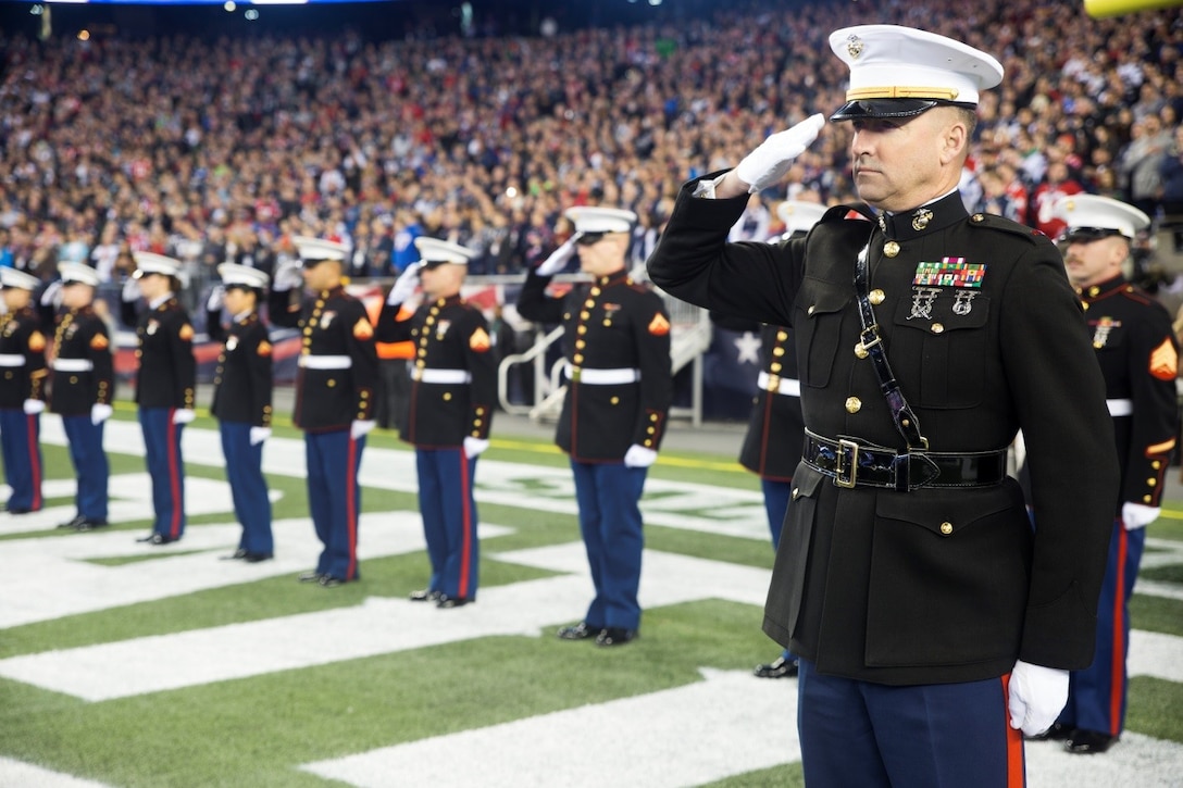 Chief Warrant Officer 3 Michael J. Smith, band officer of Marine Corps Band New Orleans, and other members of the band salute the flag throughout the playing of the National Anthem during the New England Patriots game against the Seattle Seahawks at Gillette Stadium, Nov. 13, 2016. The band performed a Centennial themed concert at halftime of the game as part of the commemoration of 100 years of the Marine Corps Reserve. Reserve Marines have served alongside their active duty counterparts in every clime and place for 100 years, leaving an indelible mark on the battle history of the Marine Corps.   (U.S. Marine Corps photo by Cpl. Melissa Martens/ Released) 
 

