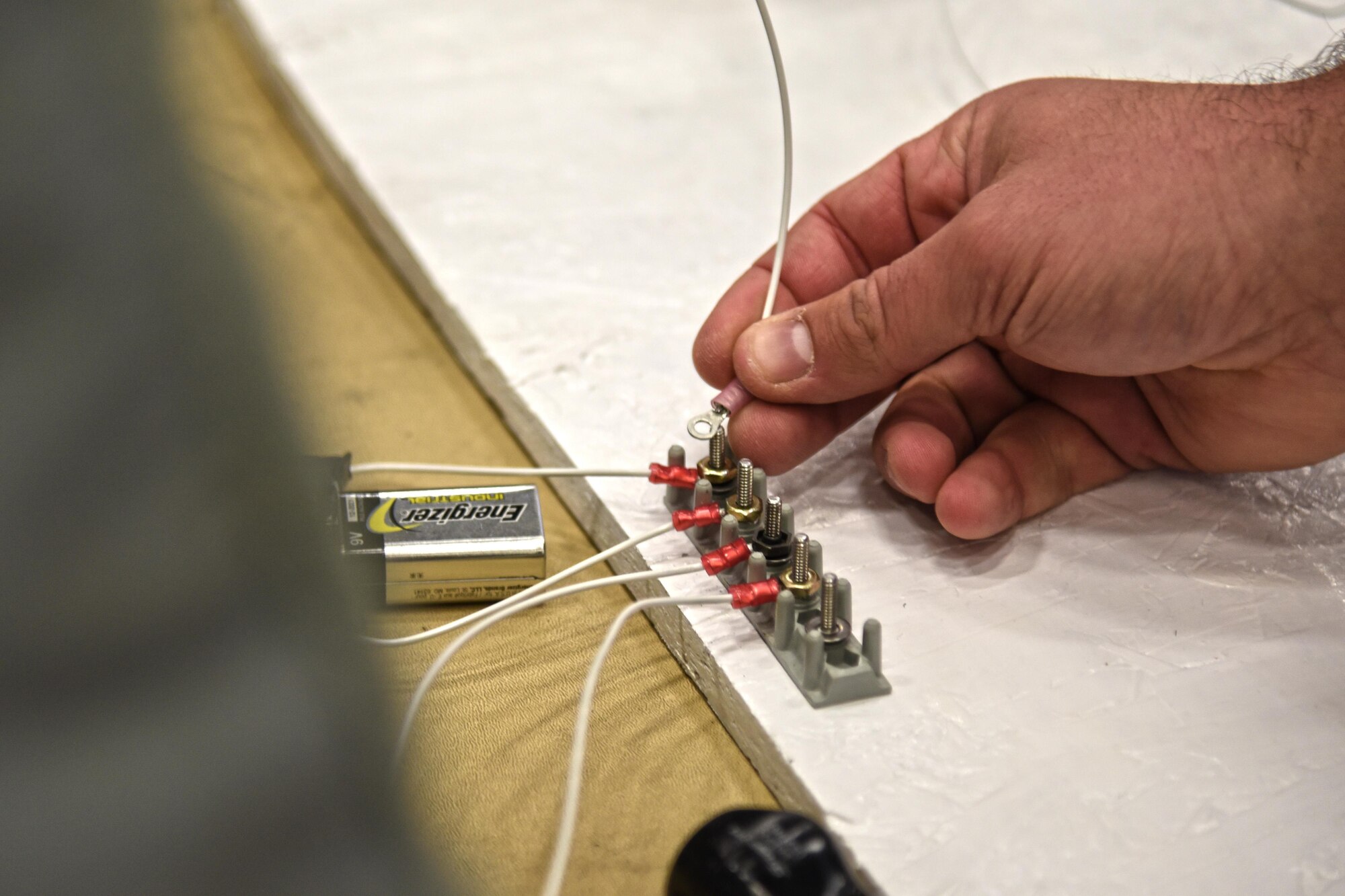 A team works on completing the circuit board challenge during the 92nd and 141st Maintenance Group Fall Olympics Nov. 15, 2015, at Fairchild Air Force Base. The circuit board challenge involved wires, batteries and numerous tools with the objective being to complete a full circuit using a switch to turn on a light bulb. The circuit board included a switch, circuit breaker, switch board, various connections and a light bulb. (U.S. Air Force photo/Senior Airman Mackenzie Richardson)
