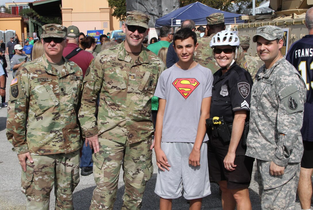 SAN ANTONIO - Local police officer Donna Marti and son Zane pose with soldiers in front of the1st Cavalry static display at the ‘Army vs Irish’ game held at the Alamodome November 12, 2016. As part of the Alamodome static display section, the 1st Calvary provided a M2 Bradley Fighting Vehicle for the public to experience. (Photo by Sgt. Zechariah Gerhard, 345th Public Affairs Detachment)