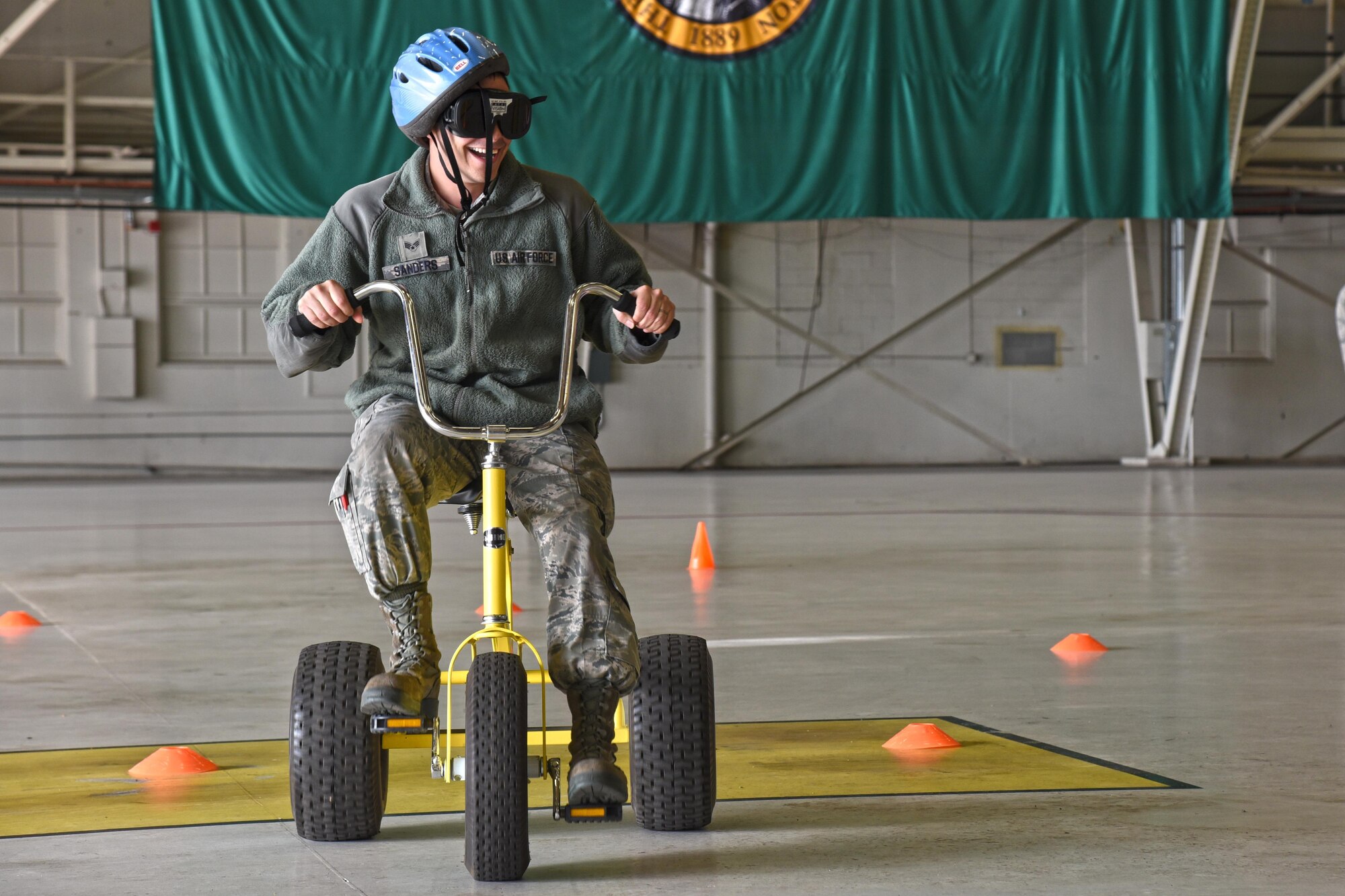 Senior Airman Edwin Sanders, 92nd Aircraft Maintenance Squadron aerospace propulsion journeyman, participates in the drunken tricycle obstacle course during the 92nd and 141st Maintenance Group Fall Olympics Nov. 15, 2016, at Fairchild Air Force Base. The obstacle course consisted of numerous gates and pathways to navigate through while wearing drunk goggles that simulated vision of having a blood alcohol content of double the legal limit. (U.S. Air Force photo/Senior Airman Mackenzie Richardson)
