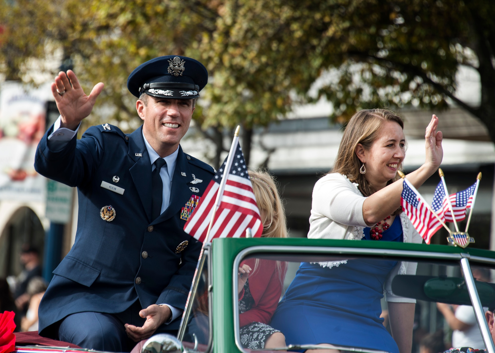 Col. John Klein Jr., 60th Air Mobility Wing commander, and his wife and daughter wave to cheering crowds as they ride through downtown Fairfield, Calif, during the town’s annual Veterans Day Parade Nov. 11, 2016. Klein was the grand marshal of the parade, which lasted two-and-a-half hours with over 70 entries.   (U.S. Air Force Photo by T.C. Perkins Jr.)
