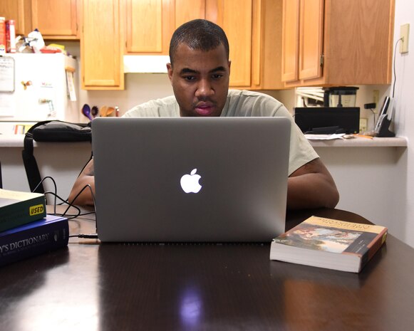 Tech. Sgt. Christopher McShan II, 341st Civil Engineer Squadron emergency management flight section chief, works on his computer at his home at Malmstrom Air Force Base, Mont., Nov. 17, 2016. McShan recently received his conferral date for his college graduation Nov. 15, and is expected to graduate May 2018. (U.S. Air Force photo/Senior Airman Jaeda Tookes)