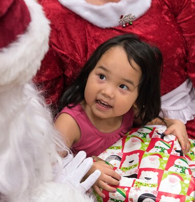 TOGIAK, Alaska -- Cassadee Mooore, 3, beams up at Santa in the school gymnasium here Nov. 15, 2016. The Clauses were here as part of Operation Santa Claus, an Alaska National Guard-led program that delivers toys, school supplies and other gifts to children in Alaska's remote villages. Air National Guard photo by Maj. John Callahan.