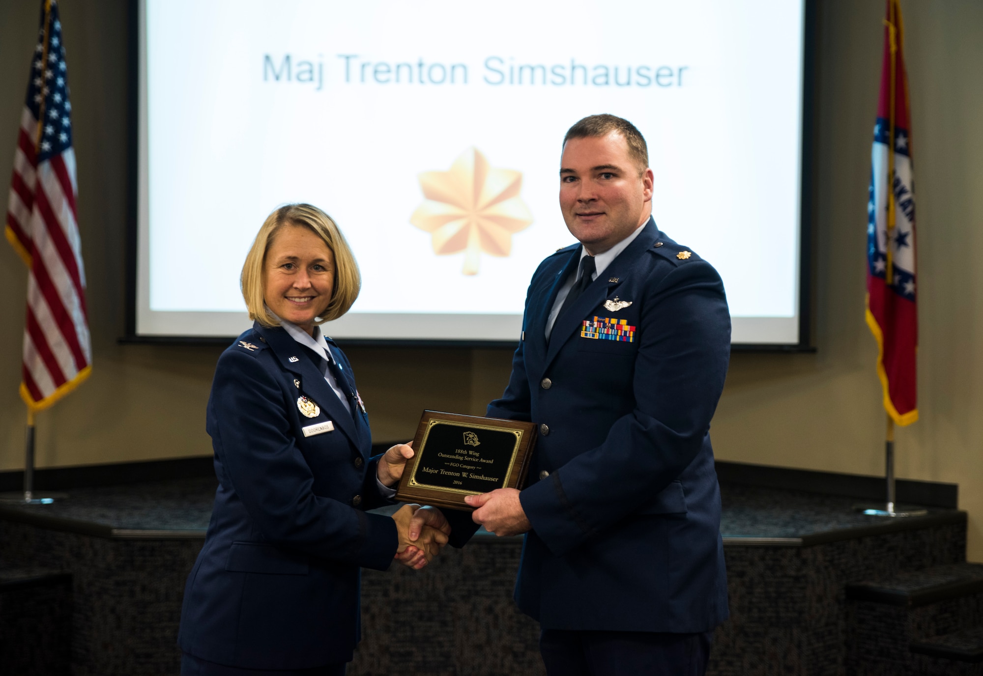 Maj. Trenton Simshauser, 184th Attack Squadron, is awarded the 2016 Outstanding Service award, Field Grade Officer category, Nov. 5, 2016, at Ebbing Air National Guard Base, Fort Smith, Ark. The Outstanding Airman of the Year program promotes professional development, innovation and mission success by recognizing those who excel in their carrier fields while fostering the cultivation of ready, responsive and highly-skilled Airman. The award was presented to Simshauser by Col. Bobbi Doorenbos, 188th Wing commander. (U.S. Air National Guard photo by Senior Airman Cody Martin)