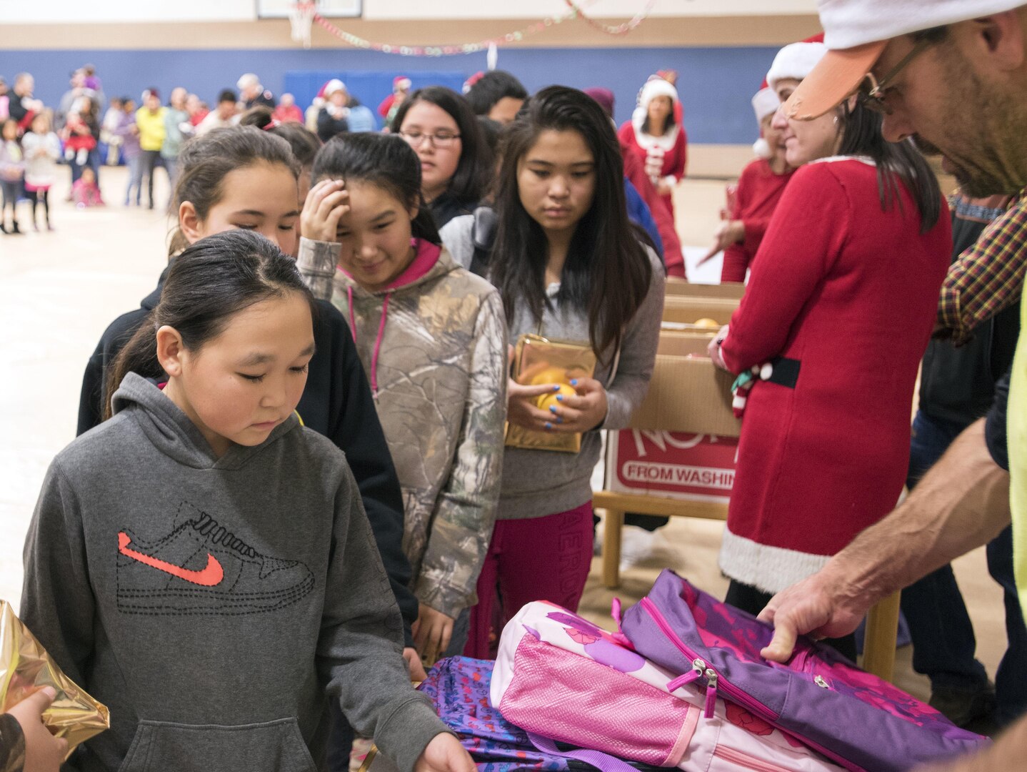 Togiak schoolgirls receive backpacks in the school gymnasium Nov. 15, 2016. Several donors were there as part of Operation Santa Claus, an Alaska National Guard-led program that delivers toys, school supplies and other gifts to children in Alaska's remote villages.