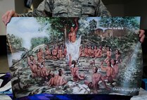 Staff Sgt. Nathan Faehl, 86th Civil Engineering Squadron Airman dorm leader, holds a poster at Ramstein Air Base, Germany, Nov. 15, 2016. The poster is a copy of the mural Otath-he-waugh-Pe-Qua, meaning “he has come out from the ashes”, originating from Piqua, Ohio. (U.S. Air Force photo by Airman 1st Class Savannah L. Waters)