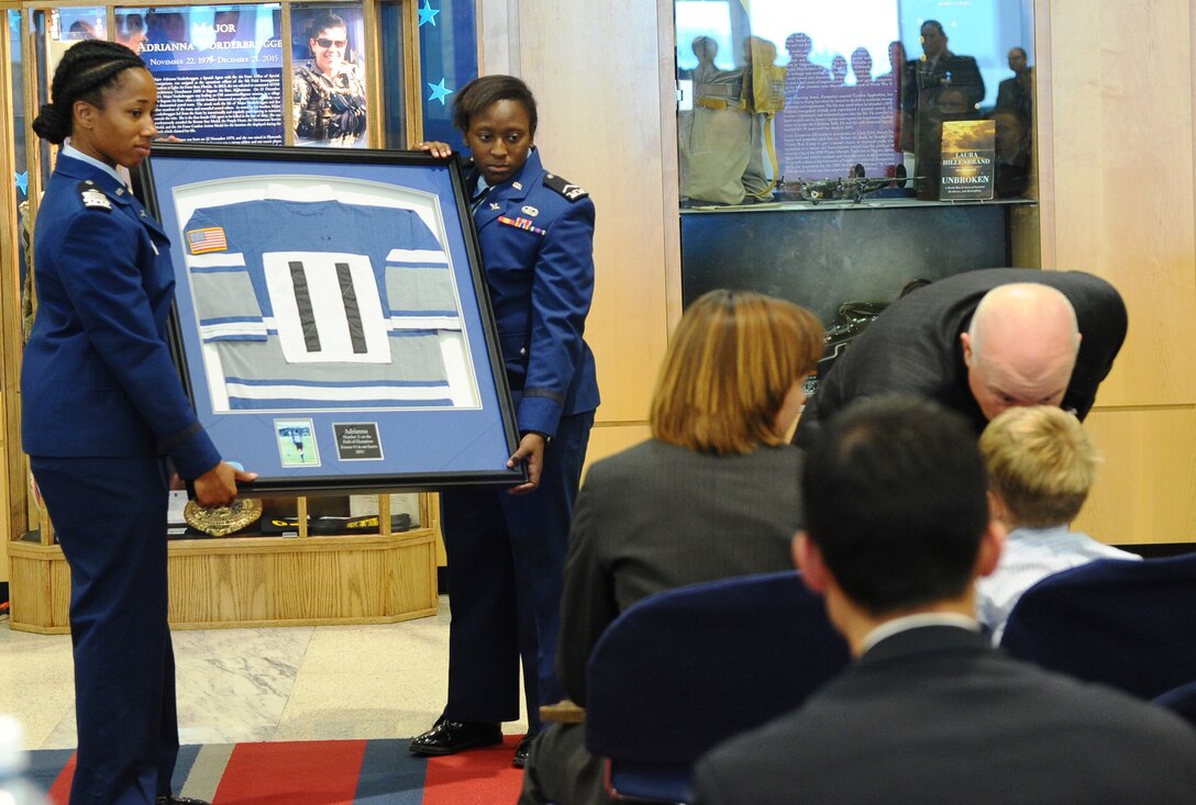 Cadets from Cadet Squadron 02 hold a frame containing a Women's Rugby Team jersey with the number worn by Maj. Adrianna Vorderbruggen, Nov. 12, 2016, at the U.S. Air Force Academy. Vorderbruggen, a 2002 Academy graduate and member of the national championship-winning rugby team, was a U.S. Air Force Office of Special Investigations agent who died last year in Afghanistan. Her family, friends and OSI coworkers dedicated a memorial in her honor, displayed in the hallway near CS02. (U.S. Air Force photo/Tech. Sgt. Mike Slater) 