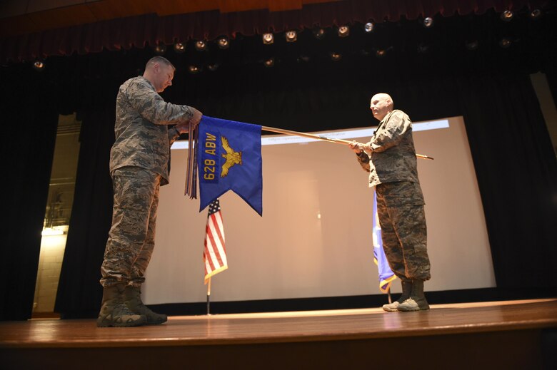Col. Robert Lyman, Joint Base Charleston commander, and Chief Master Sgt. Todd Cole, 628th Air Base Wing command chief, present the Global War on Terror services streamer to the 628th ABW in the Air Base Theater during a commander’s call Nov. 17, 2016. General Carlton D. Everhart II, Air Mobility Command commander, authorized the service streamer on July 15, 2016, for direct support of Global War on Terror operations from Jan. 8, 2010, to present.