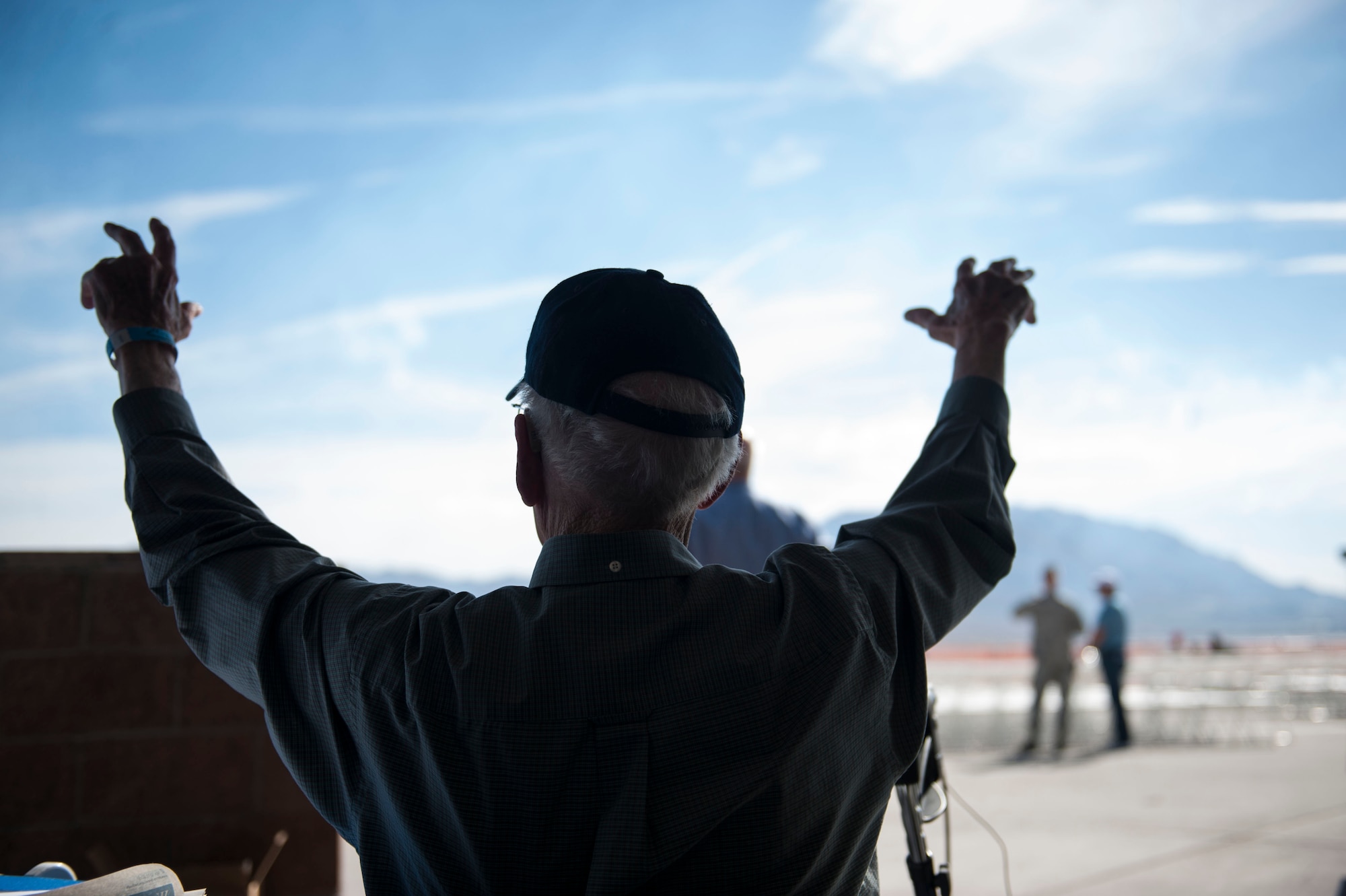 Lenoard Nielson, U.S. Navy Pearl Harbor survivor raises his hands with excitement during the Aviation Nation air show at Nellis Air Force Base, Nev., Nov. 12. This year, Aviation Nation celebrated 75 years of Air Power through the Air Force’s accomplishments  in air, space and cyberspace. During the two-day event, there were more than 50 aircraft on display along with an array of vendors and aerial demonstrations for viewers. (U.S. Air Force photo by Senior Airman Rachel Loftis/released)