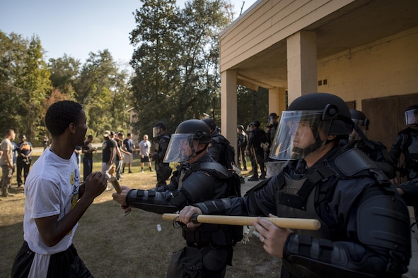 Georgia State Patrol’s Mobile Field Force police officers stand together during riot training as Airman 1st Class David Gardener, an 822nd Base Defense Squadron security forces apprentice and riot role-player, attempts to break through the line Nov. 16, 2016, at Moody Air Force Base, Ga. Airmen were directed to behave differently each time a scenario began to test the GSP officers’ responses. (U.S. Air Force photo/Airman 1st Class Daniel Snider)