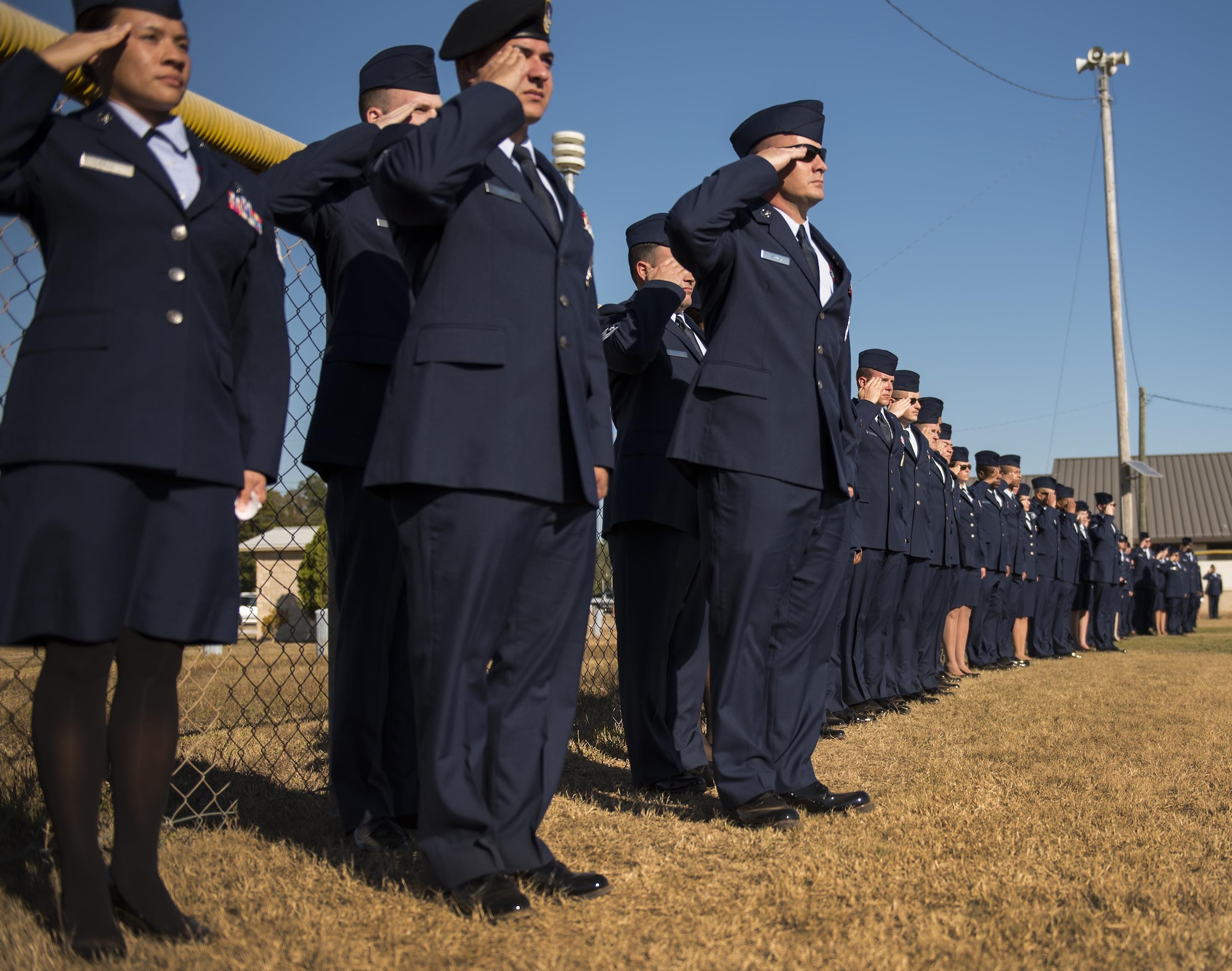 Airmen salute during the playing of the National Anthem prior to their entrance at the beginning of the Community College of the Air Force graduation ceremony at Eglin Air Force Base, Fla., Nov. 16.  More than 300 Airmen from Eglin and Duke Field were honored at this year’s event. (U.S. Air Force photo/Samuel King Jr.)