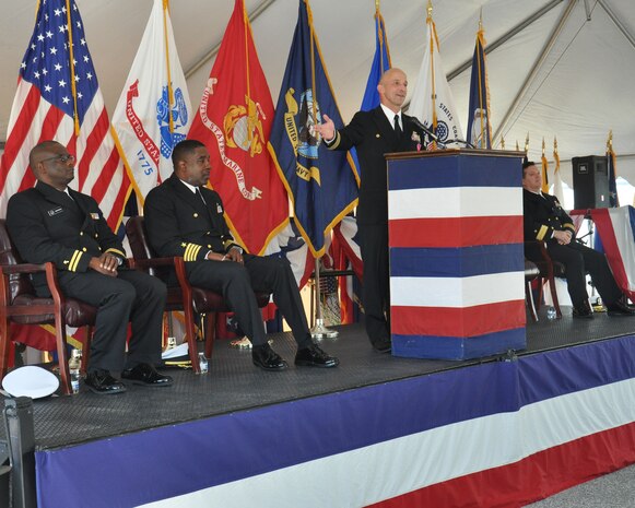 Capt. Brian Durant, standing, outgoing commanding officer of the Naval Surface Warfare Center Dahlgren Division (NSWCDD), thanks the men and women of the command for all their hard work and accomplishments during his tenure at NSWCDD's change of command ceremony Nov. 18 at Naval Support Facility (NSF) Dahlgren. From left to right are Lt. Joshua Okwori, Naval Support Activity South Potomac (NSASP) command chaplain, Capt. Godfrey Weekes, incoming NSWCDD commanding officer, Durant, and Rear Adm. Tom Druggan, commander of the Naval Surface Warfare Center (NSWC). 