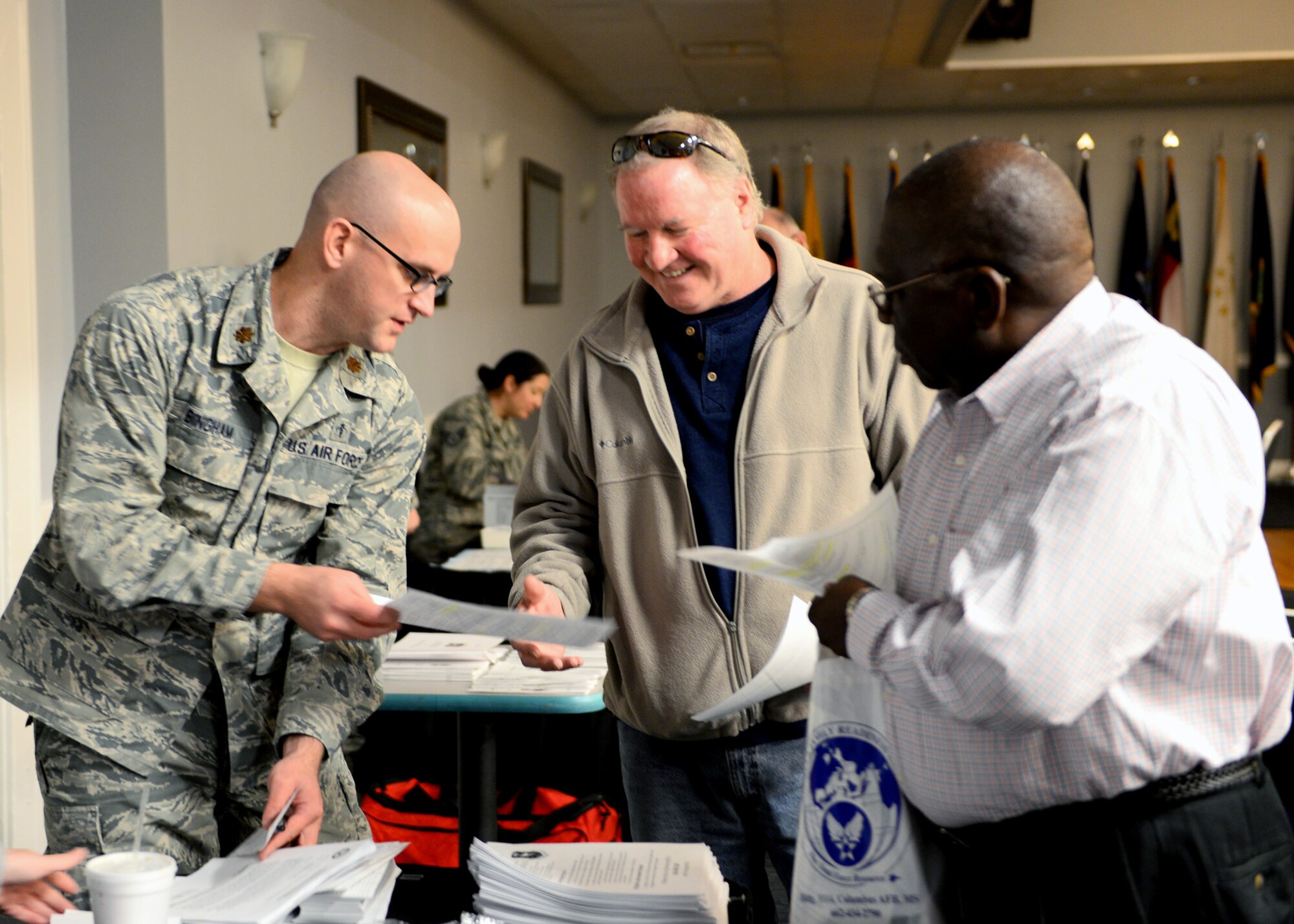 Maj. Jason Bingham, 14th Medical Support Squadron, hands Air Force retirees Walt Boltwood and Joe Smith information about upcoming changes to the pharmacy health insurance policy Nov. 16, 2016, at Columbus Air Force Base, Mississippi. During the event attendees were able to learn about a variety of programs in place to support them, including the retiree affairs office, Koritz Clinic, Airman and Family Readiness services, and the base commissary upgrade project. Afterwards retirees were able to gather pamphlets, fill out medical cards, and receive free flu shots. (U.S. Air Force photo by 1st Lt. Lauren Woods)