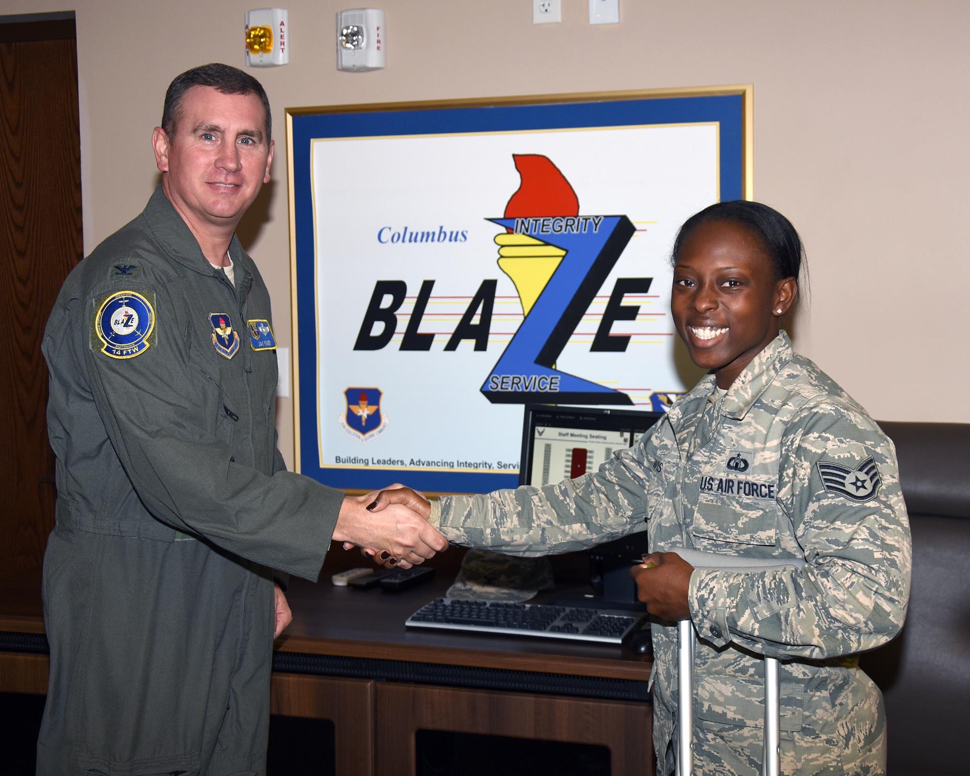 Col. James Fisher coins Staff Sgt. Lewis Fredritta, 14th Operations Support Squadron, Oct. 26, 2016, at Columbus Air Force Base, Mississippi, for her Green Dot efforts. Lewis, currently working in Honor Guard, went to a concert in Tuscaloosa, Alabama. Upon leaving the concert she saw an intoxicated young woman having trouble walking. Lewis went to assist and the young woman passed out. Lewis then started to carry the woman to security when a man came up to assist stating that he would take her. Lewis asked the man if he knew the woman and what her name was. He then left upon questioning. Lewis practiced her reactive Green Dot skills and was able to get the woman to safety and prevent a possible incident from happening. (U.S. Air Force photo by Sharon Ybarra)