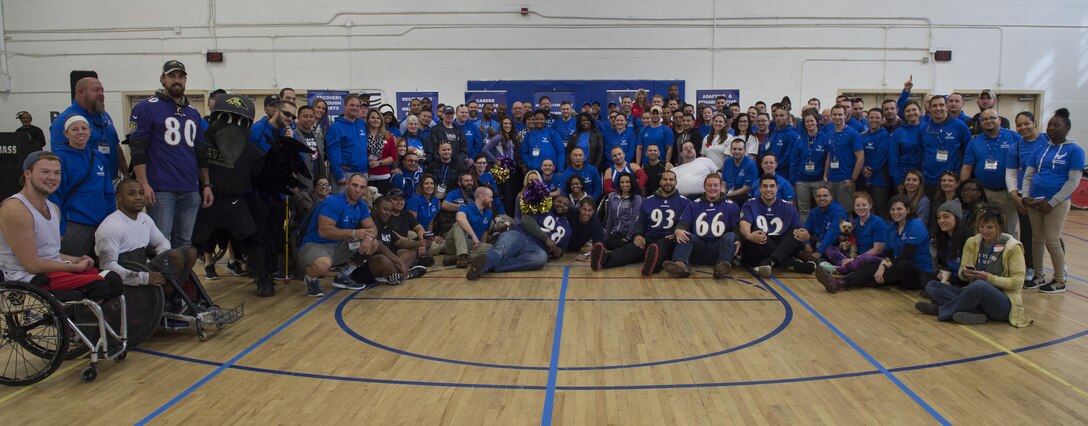 Wounded Warriors, coaches and volunteers come together with Baltimore Ravens players, cheerleaders and mascot to take a group photo during the Northeast Region Warrior CARE Event at Joint Base Andrews, Md., Nov. 14, 2016. Ravens representatives made an appearance to show their support during the opening of the Warrior CARE week. The events are a part of a week-long program that features education in Caregiver Support, Adaptive and Rehabilitative Sports, Recovering Airman Mentorship, and Employment and Career Readiness. (U.S. Air Force photo by Senior Airman Philip Bryant)