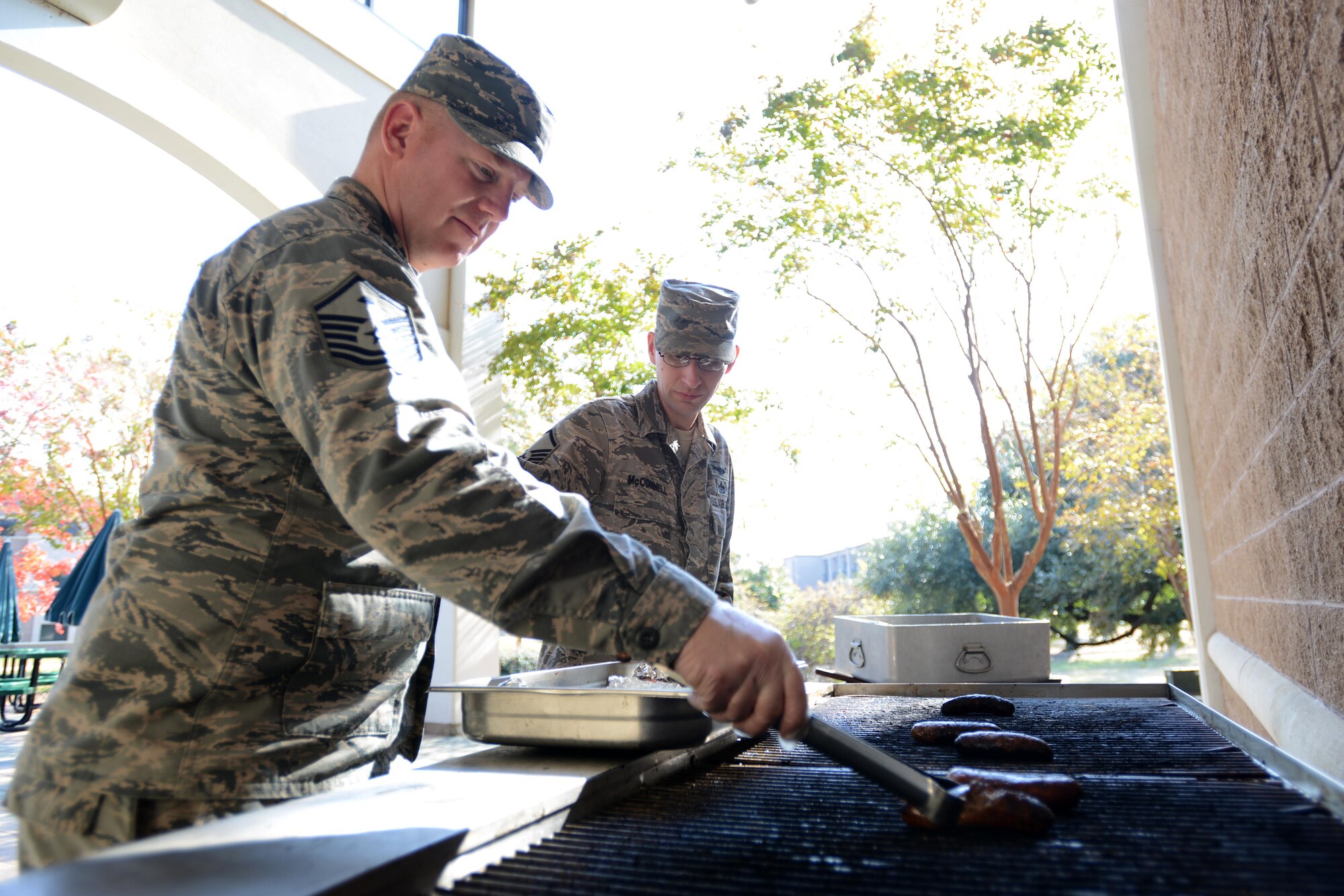 U.S. Air Force Master Sgt. Jonathan Curl, 20th Medical Group first sergeant, and Master Sgt. Jason McConnell, 20th Operations Support Squadron intelligence superintendent, cook bratwursts on a grill at Shaw Air Force Base, S.C., Nov. 16, 2016. The Shaw Diamond Council teamed up to bring food to all of the Airmen participating in operational readiness exercise Weasel Victory 17-03. (U.S. Air Force photo by Airman 1st Class Kelsey Tucker)