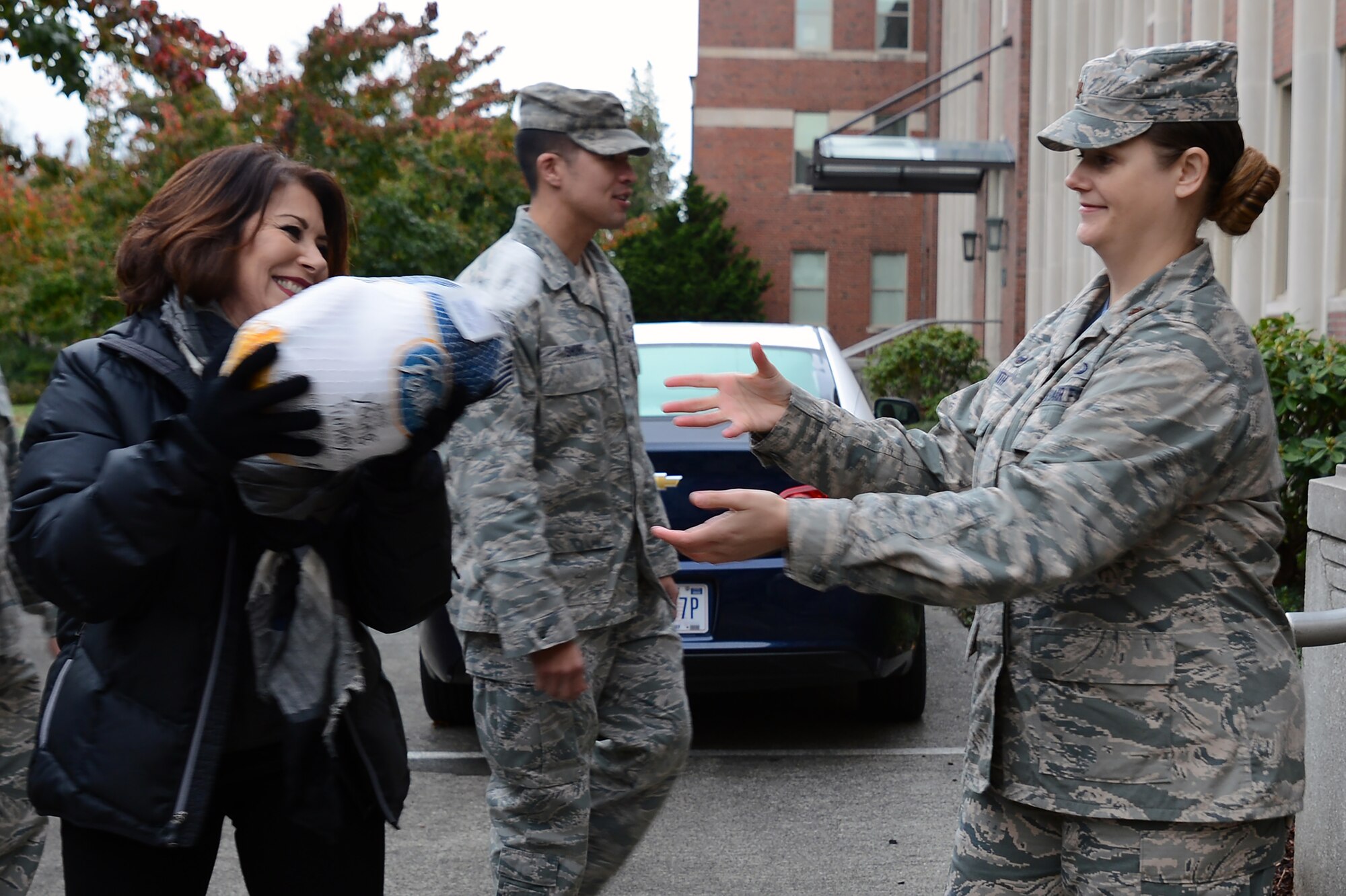 Vicky Welcher (left), Harborstone Credit Union business sales and service manager, hands off a turkey to Maj. Jennifer Smith, 62nd Airlift Wing Comptroller Squadron commander, during the Annual Operation Turkey Drop Nov. 18, 2016 at Joint Base Lewis-McChord, Wash. The event was sponsored by Puget Sound community partners to help assist Airmen In need during the holidays. (U.S. Air Force photo/Senior Airman Jacob Jimenez) 
