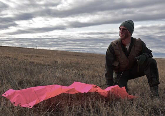 A pilot assigned to the 28th Bomb Wing, Ellsworth Air Force Base, S.D., waits for rescue at a simulated crash site near Belle Fourche, S.D., Nov. 16, 2016. The bright tarp laid out on the ground is a way to attract the attention of rescue pilots without drawing unwanted attention from hostile ground forces. (U.S. Air Force photo by Airman 1st Class James L. Miller) 