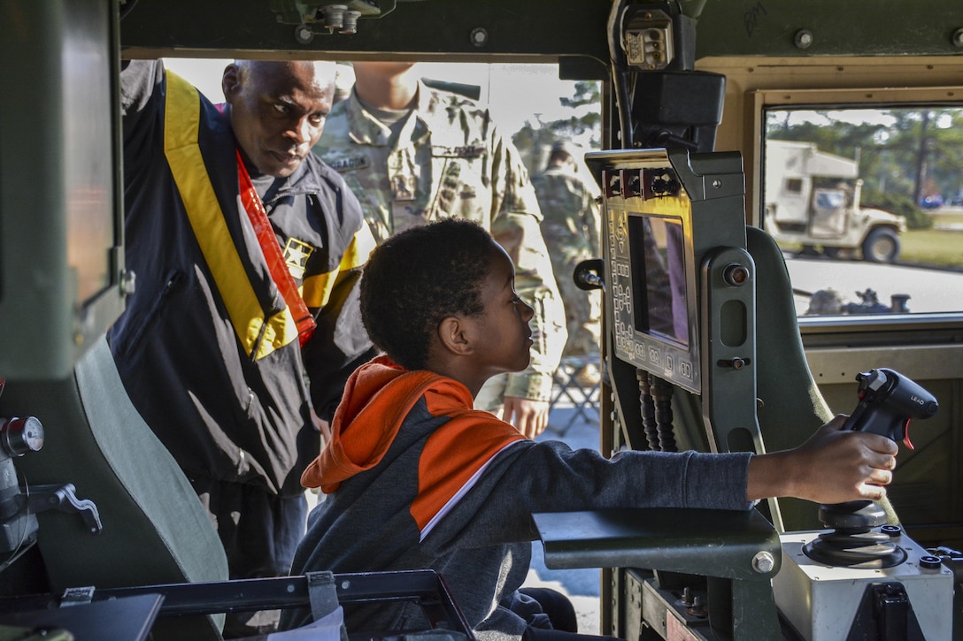 Army Staff Sgt. Elvis Cesar shows his son, Zackhery, around Marne Week's static display at Fort Stewart, Ga., Nov. 16, 2016. Zackhery operates a remotely operated weapon station inside a  multipurpose wheeled vehicle. Cecar is assigned to 1st Battalion, 41st Field Artillery Regiment, Division Artillery. Army photo by Sgt. Caitlyn C. Smoyer