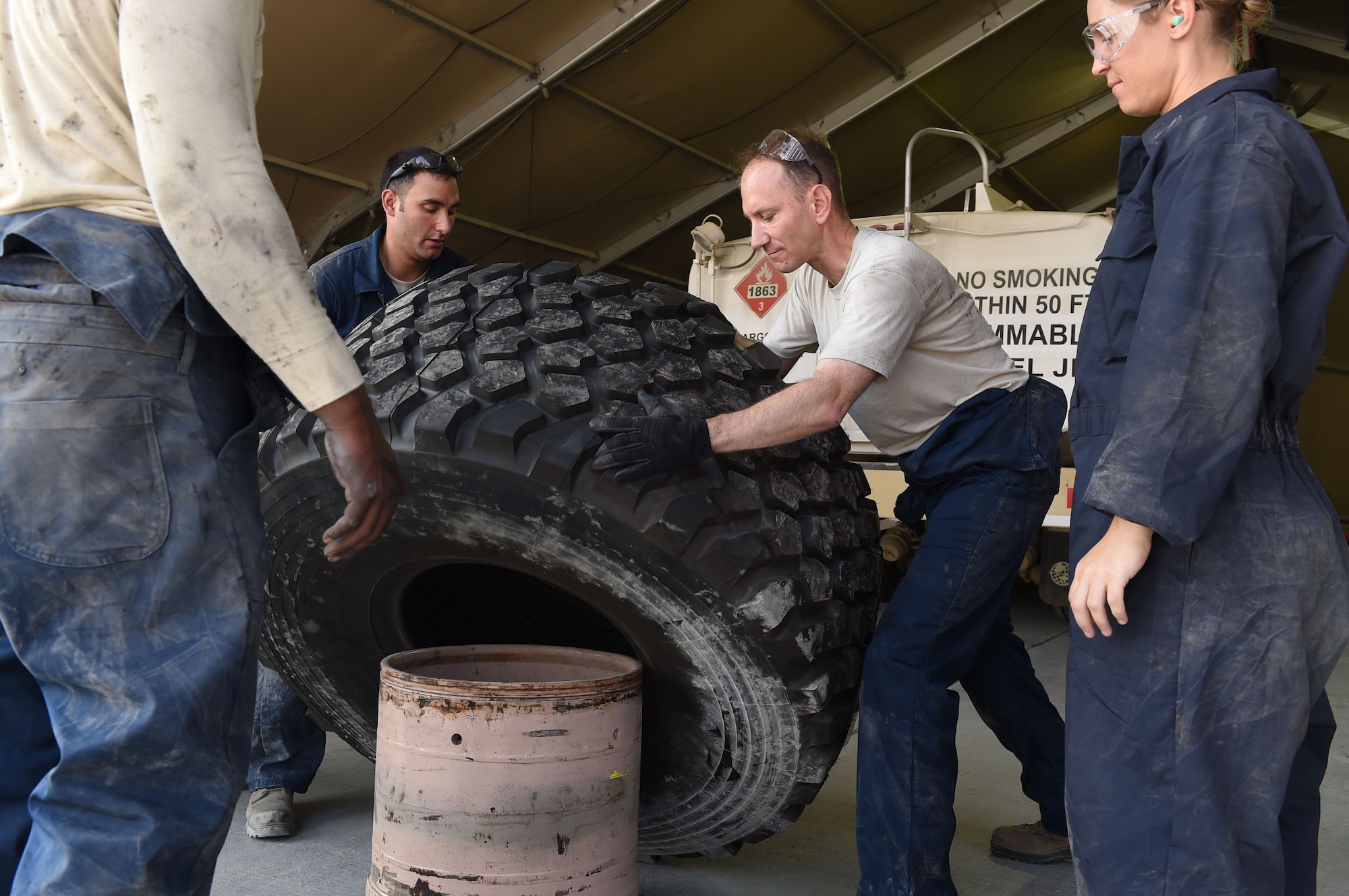 Col. Kevin Eastland, 380th Air Expeditionary Wing vice commander, works with Senior Airman Johnathan, 380th Fire and Refueler Maintenance vehicle maintainer, to flip a new tire onto a rim for a fire truck at an undisclosed location in Southwest Asia, November 16, 2016. With only a few fire trucks, FARM vehicle maintainers have to be diligent in completing required maintenance in order to quickly return the trucks back to operational status and supporting the 380th AEW mission. (U.S. Air Force photo by Tech. Sgt. Christopher Carwile)