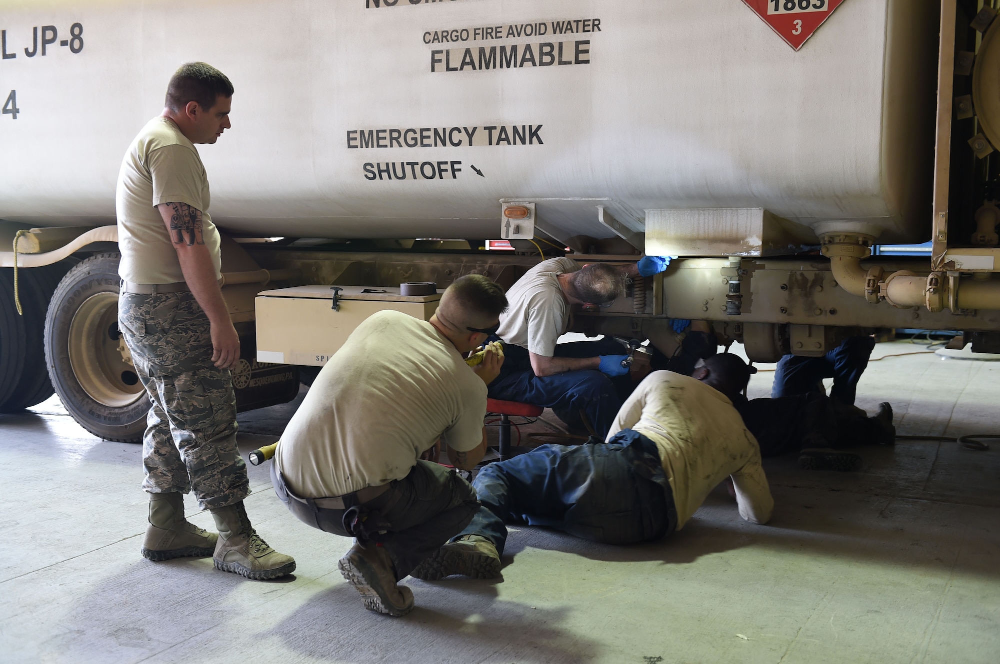 380th Fire and Refueler Maintenance members observe and advise Col. Kevin Eastland, 380th Air Expeditionary Wing vice commander, in removing the paint from an R-11 fuel truck tank sump at an undisclosed location in Southwest Asia, November 16, 2016. A problem was noticed with R-11 tank sumps and the manufacturer sent out a service kit to better support the tanks, which requires removing paint from part of the tank to properly attach the kit. (U.S. Air Force photo by Tech. Sgt. Christopher Carwile)