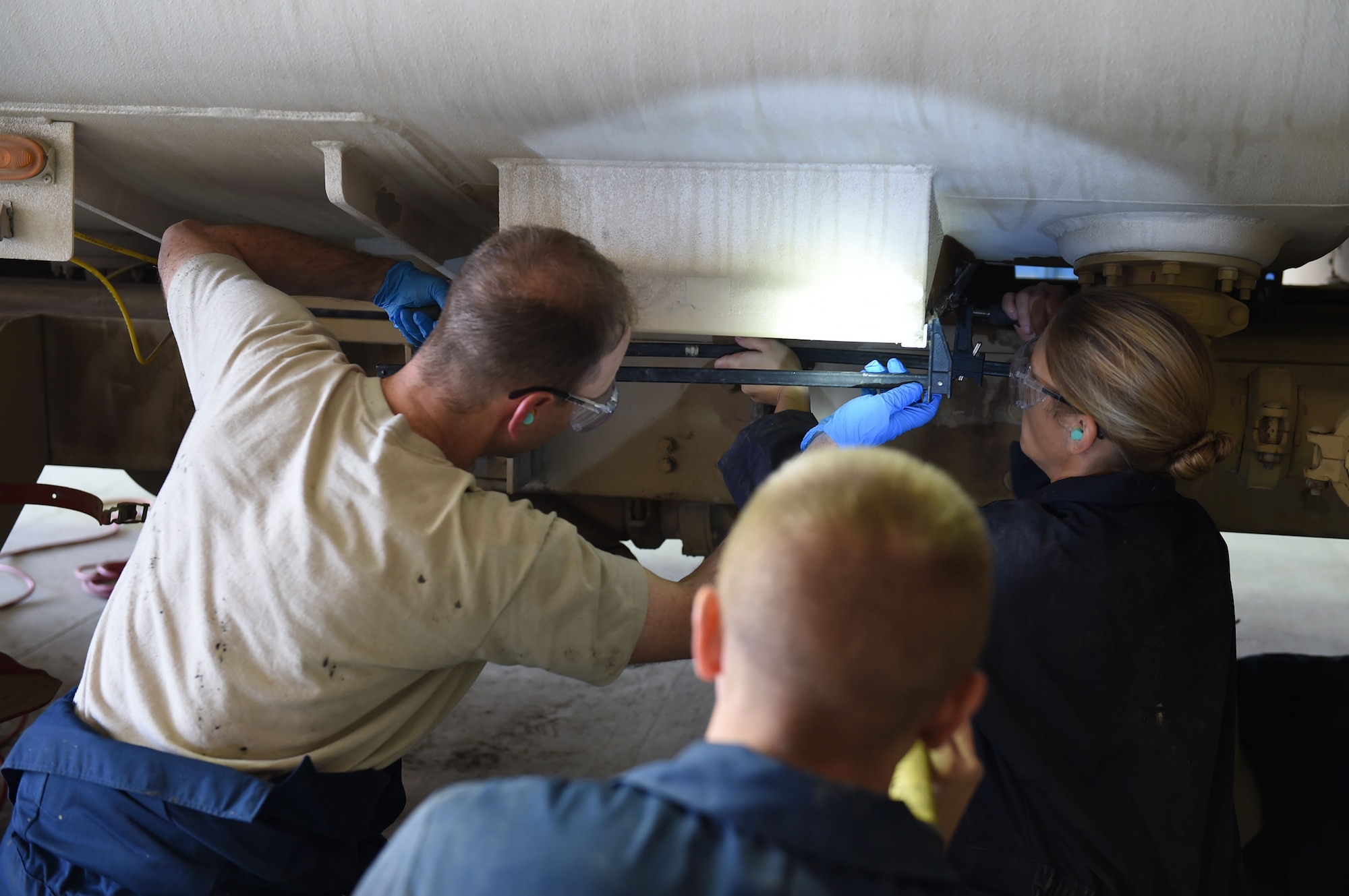 Col. Kevin Eastland, 380th Air Expeditionary Wing vice commander, and Capt. Jennifer, 380th AEW executive officer, use clamps to hold freshly mounted angle beams to an R-11 tank sump while the industrial acrylic adhesive cures at an undisclosed location in Southwest Asia, November 16, 2016. Eastland and Jennifer joined the Fire and Refueler Maintenance shop for the morning as a chance to get out and work with the Airmen that are supporting the 380th AEW mission every day. (U.S. Air Force photo by Tech. Sgt. Christopher Carwile)