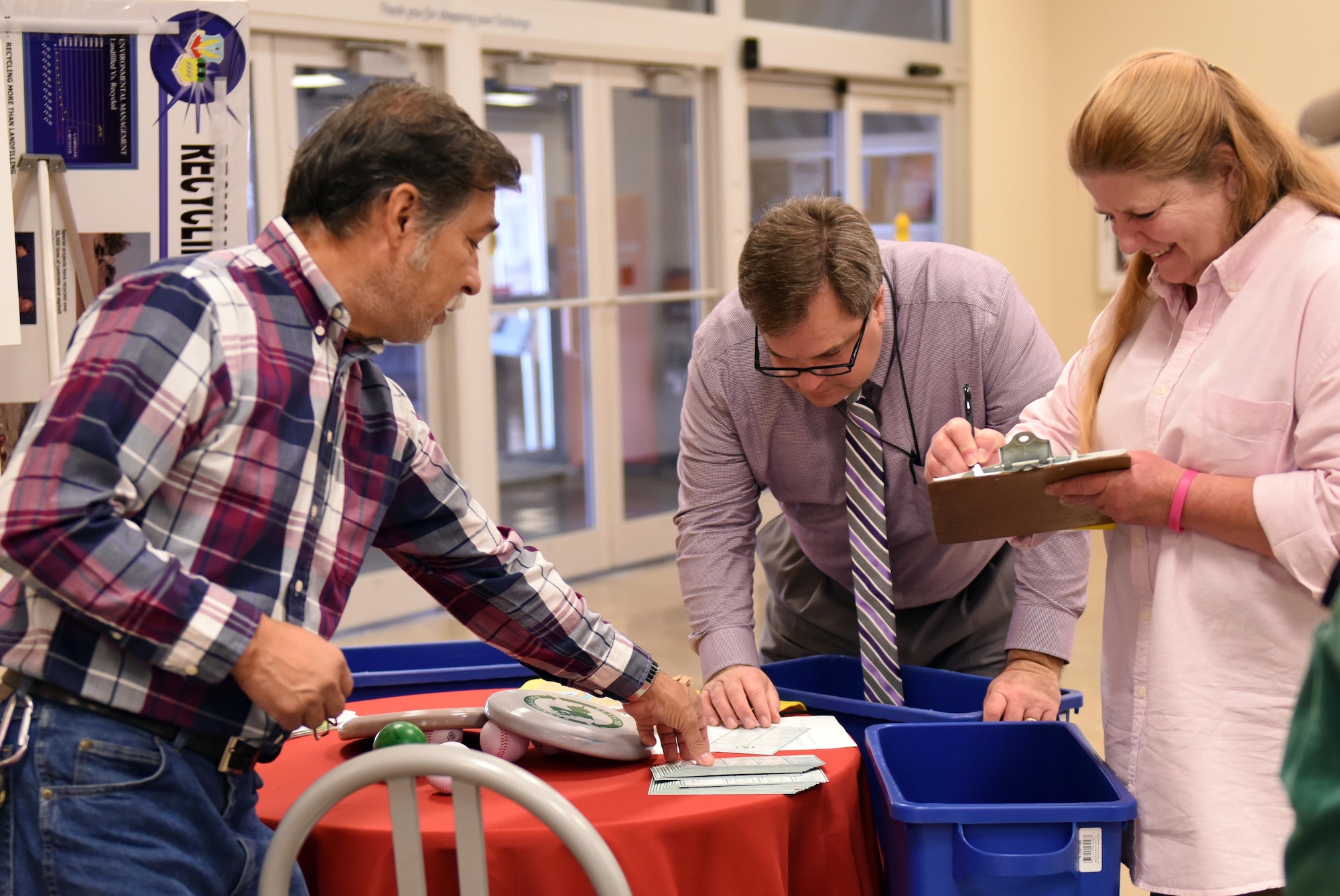 Alfredo Garza, left, 2nd Civil Engineer Squadron recycling manager, speaks with patrons at a recycling booth at Barksdale Air Force Base, La., Nov. 15, 2016. Barksdale raised recycling awareness in support of the national initiative of America Recycles Day to keep America beautiful. (U.S. Air Force photo/Airman Alexis C. Schultz)
