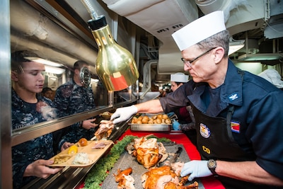 Navy Capt. Mike Wettlaufer, commanding officer aboard the aircraft carrier USS John C. Stennis (CVN 74), serves turkey during a Thanksgiving meal Nov. 26, 2015. DLA Troop Support’s Subsistence supply chain provides service members around the world a taste of home for Thanksgiving every year.