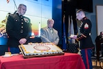 Oldest Marine Sgt. Gary A. Rodgers passes cake to Sgt. Austin Reed, the youngest Marine during the cake cutting ceremony that serves as the hallmark of the Marine Corps birthday ceremony.