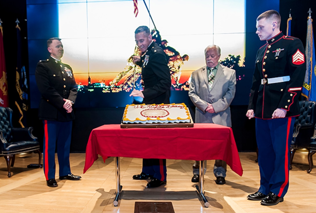 Lt. Col. Kirk Greiner, the senior Marine assigned to Land and Maritime, cuts the Marine Corps Birthday cake Nov. 9. On stage with Greiner is USMC Lt. Col. Michael D. McCarthy (left), guest speaker at the celebration; oldest Marine Sgt. Gary A. Rodgers; and youngest Marine Sgt. Austin Reed.