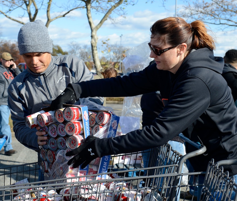 U.S. Air Force Master Sgt. Dathan Hayes, 633rd Communications Squadron first sergeant, and Jennifer May, wife of Master Sgt. Philip May, 633rd Medical Group first sergeant, unwrap canned goods during the for Operation Warmheart at Joint Base Langley-Eustis, Va., Nov. 20, 2016. The Langley First Sergeant Council hosts the Operation Warmheart Thanksgiving basket drive annually to gather food for JBLE service members and their families. (U.S. Air Force photo by Airman 1st Class Kaylee Dubois)