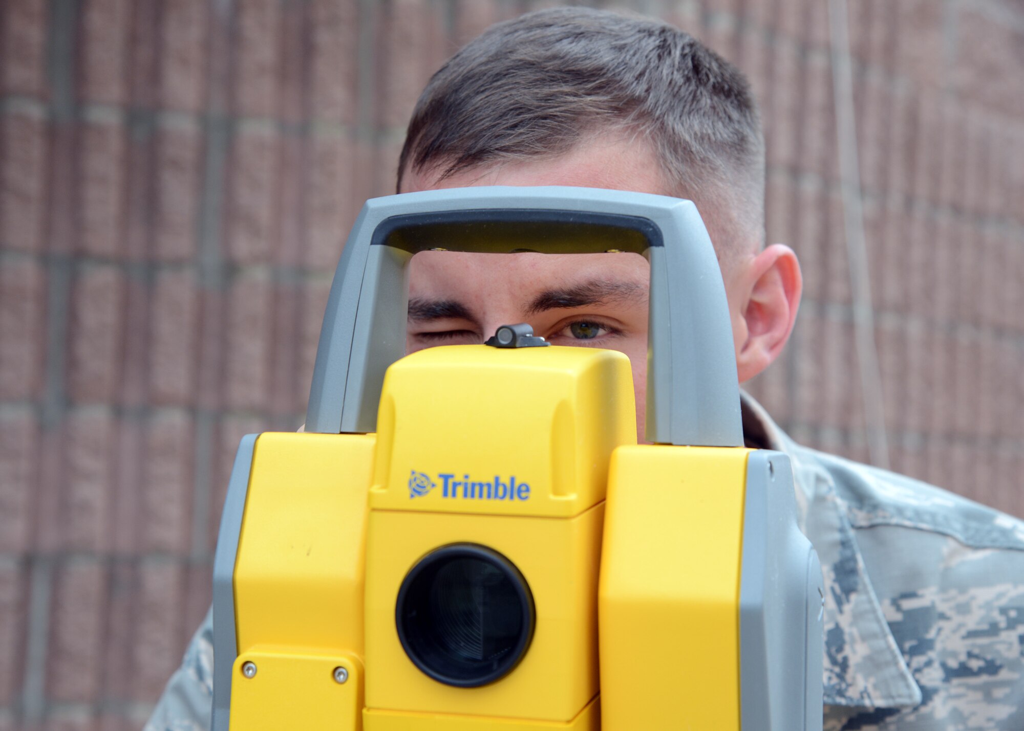 Senior Airman Ryan Holland, 56th Civil Engineer Squadron engineering technician, looks through the view finder of the Trimble Total Station 5600 during a Geographic Information Systems demonstration Nov. 16, 2016, at Luke Air Force Base, Ariz. Holland and the 56th CES engineering flight is in charge of developing maps and sketching plans for events such as an airshow or wing level events. (U.S. Air Force photo by Senior Airman Devante Williams)