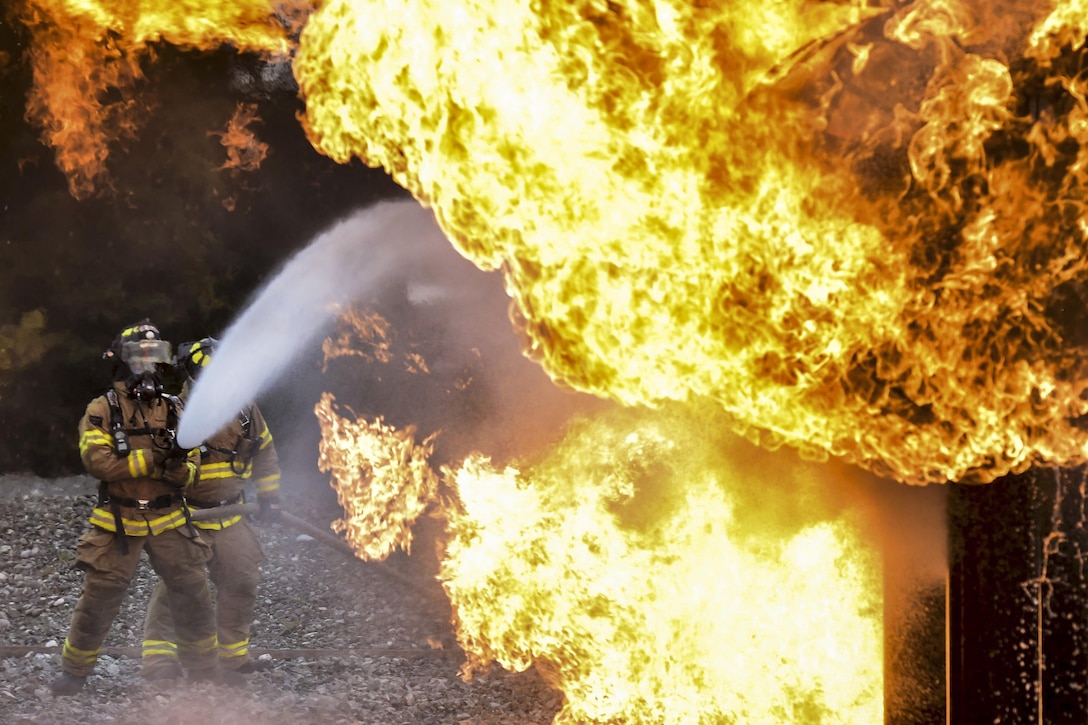 Air Force Senior Airman Larry Kyles, left, and Tech Sgt. Sean Armstrong spray down a simulated aircraft fire during firefighting training at Joint Base Elmendorf-Richardson, Alaska, Sept. 14, 2016. The airmen are assigned to the 673rd Civil Engineer Squadron. Air Force photo by Justin Connaher