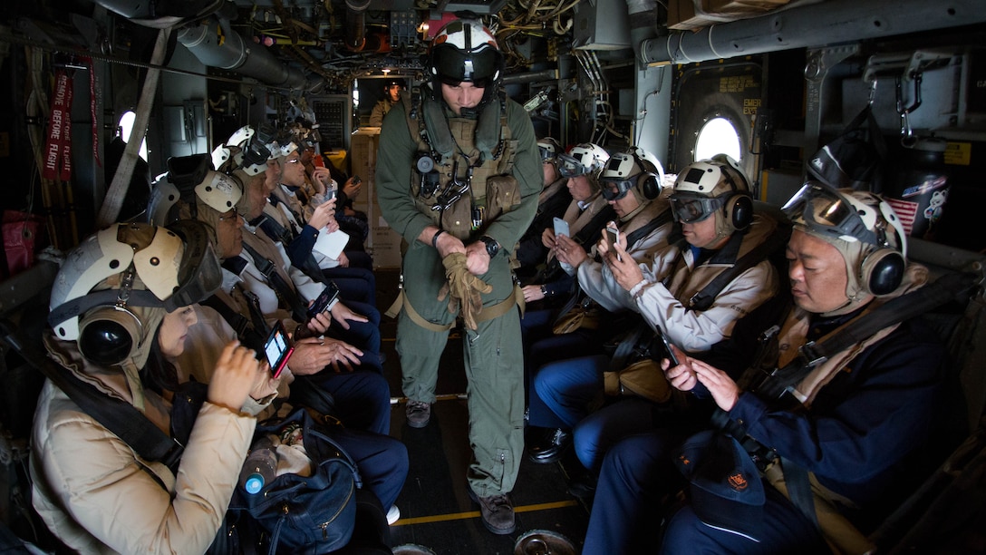 Sgt. Andrew Sturgress, a MV-22B Osprey tiltrotor aircraft crew chief assigned to Marine Medium Tiltrotor Squadron 262, 31st Marine Expeditionary Unit, walks past Mr. Norio Tomonaga, the Mayor of Sasebo, and the Assemblymen of Defense for Sasebo City during take-off preparation from Sasebo, Nagasaki, Japan, Nov. 18, 2016. The aircraft flew from the island of Okinawa, conducted simulated humanitarian aid with the Japan Maritime Self-Defense Force at multiple locations and was refueled by JMSDF personnel before returning to Okinawa. 