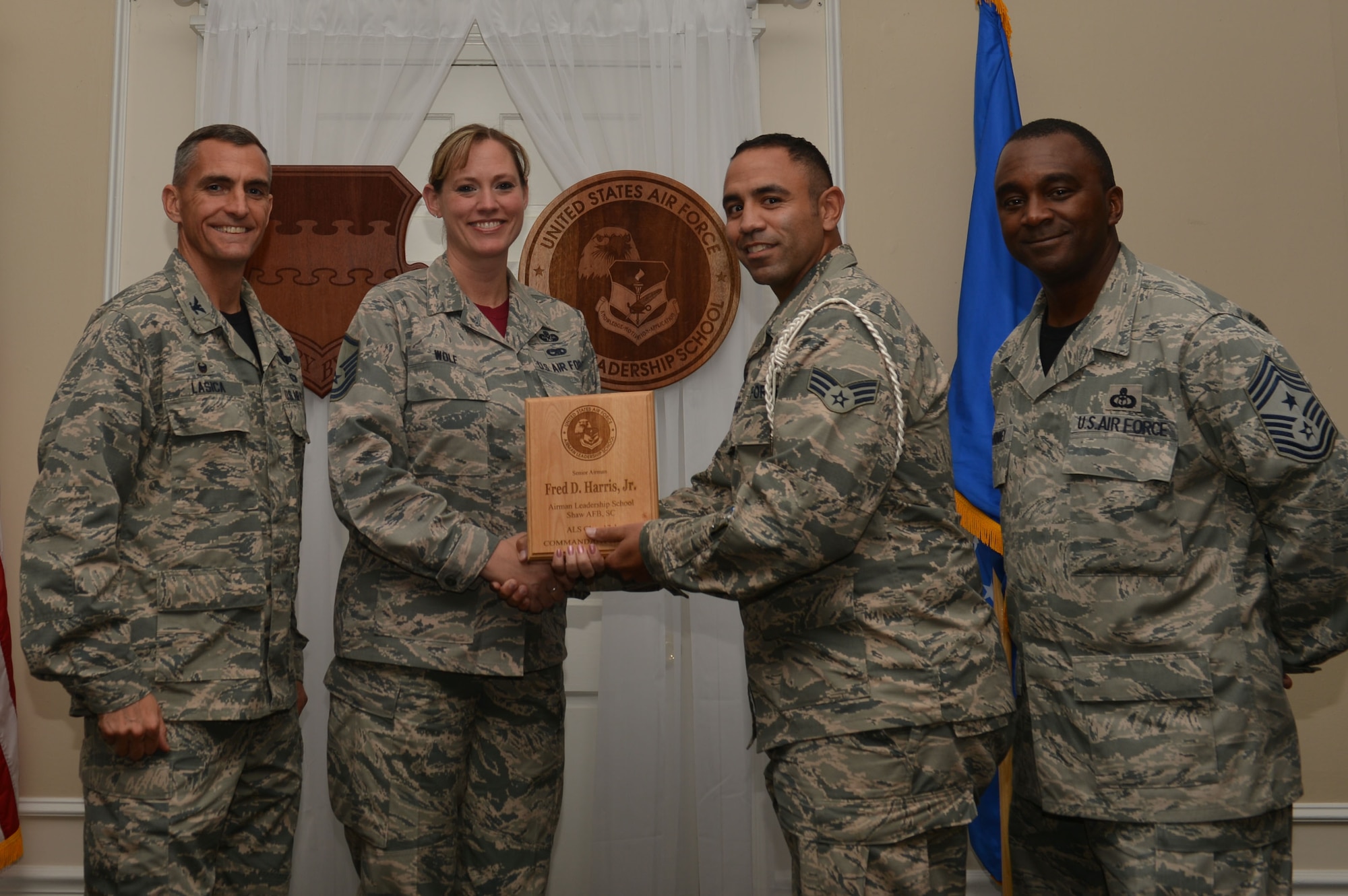 U.S. Air Force Senior Airman Fred Harris, Air Education and Training Command, 316th Training Squadron, receives the Senior Master Sgt. David B. Reid Airman Leadership School Commandant’s Award from Master Sgt. Lindsey Wolf, 20th Force Support Squadron ALS commandant, during the ALS Class 17-1 graduation at Shaw Air Force Base, S.C., Nov. 18, 2016. The Commandant’s Award is presented to the student who most exemplifies professional military qualities as chosen by their peers, the primary instructors, and the ALS commandant. (U.S. Air Force photo by Airman 1st Class Christopher Maldonado)