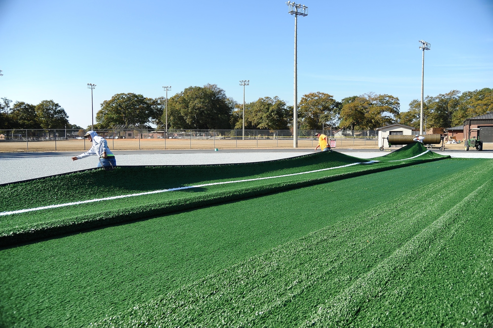 Contractors lay new turf at the base track across from the Fitness Center. The entire area is being reconstructed and is scheduled to be complete around the beginning of the new year. (U.S. Air Force photo by Misuzu Allen)