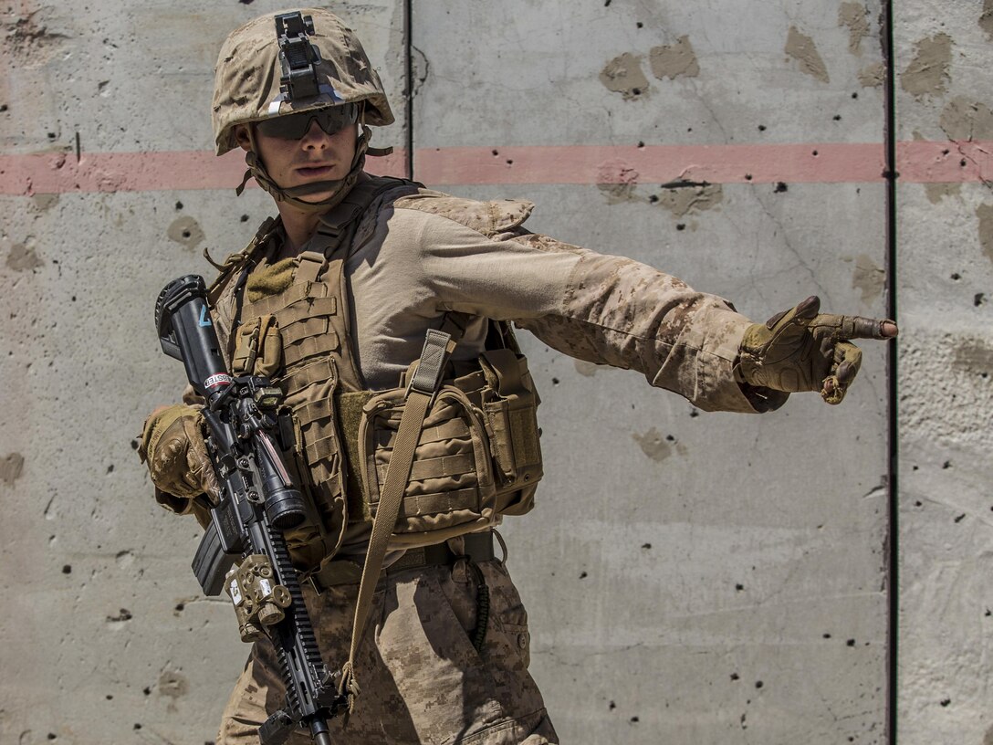 Lance Cpl. Michael Webster signals to his team while conducting a raid during the 11th Marine Expeditionary Unit’s Combined Arms Exercise at Marine Corps Air Ground Combat Center Twentynine Palms, Calif., June 12, 2016. MEUCAX enables Battalion Landing Team 1st Battalion, 4th Marines to refine their offensive and defensive tactics at the company and battalion levels. This training enables the Marines to practice transitioning from an offensive attack to the defense position, both during day and night operations. The culminating event will involve a battalion ground offensive in coordination with Marine aviation close-air support. MEUCAX is conducted to maintain a high level of combat readiness prior to the MEU’s Western Pacific 16-2 deployment later this year. Webster is a rifleman with LAR Company, Battalion Landing Team 1st Bn., 4th Marines, 11th MEU. (U.S. Marine Corps photo by Lance Cpl. Zachery Laning/Released)