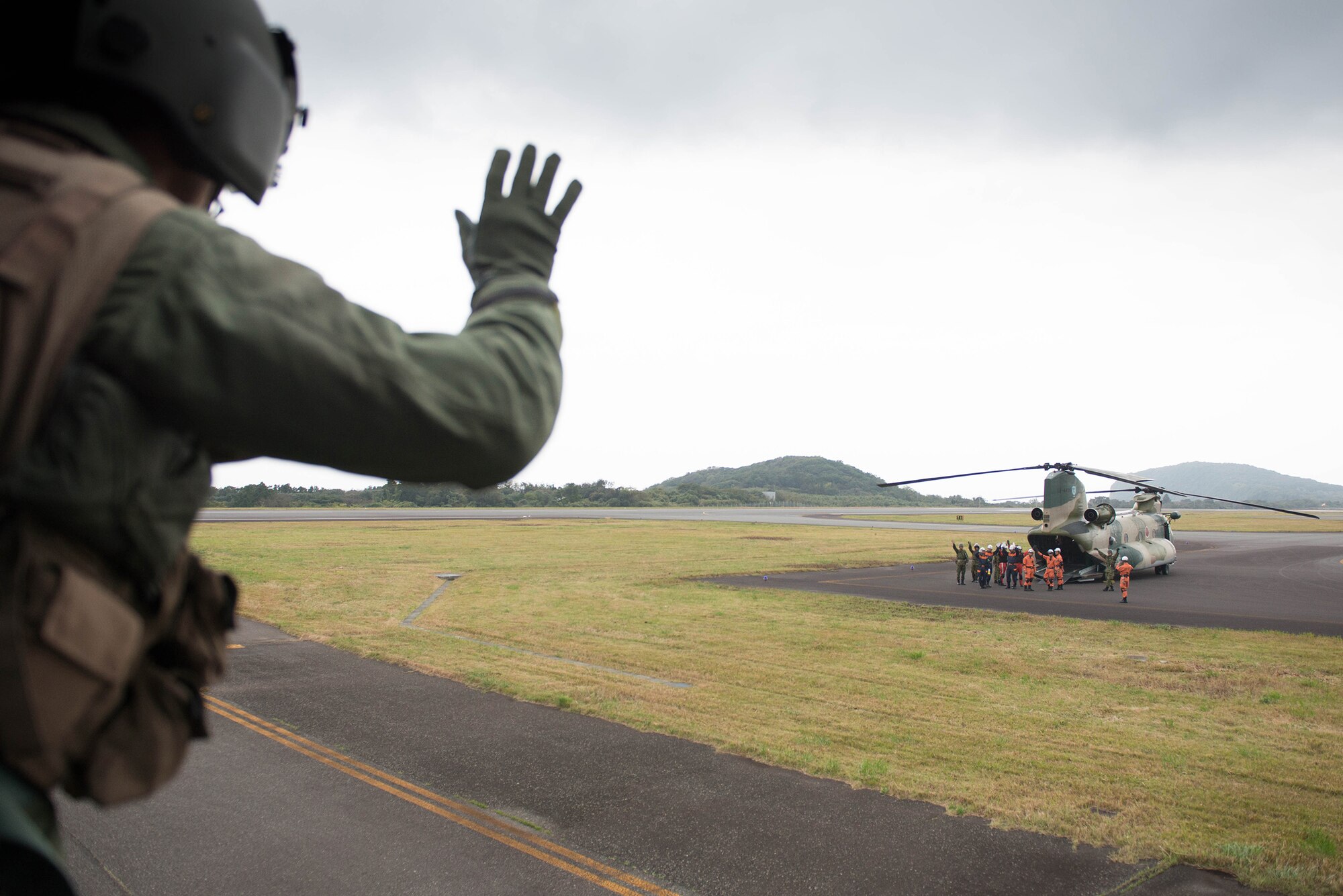 Staff Sgt. Nicholas Poe, 459th Airlift Squadron UH-1N Iroquois flight engineer, waves goodbye at Oshima Airport in Oshima, Japan, Nov. 21, 2016. Yokota’s 459 AS worked with the Japan Self-Defense Forces, U.S. Army and U.S. Navy on an exercise to deliver simulated humanitarian aid to Oshima, Japan, after a volcanic eruption. (U.S. Air Force  photo by Senior Airman Justin Carnahan/Released)                         