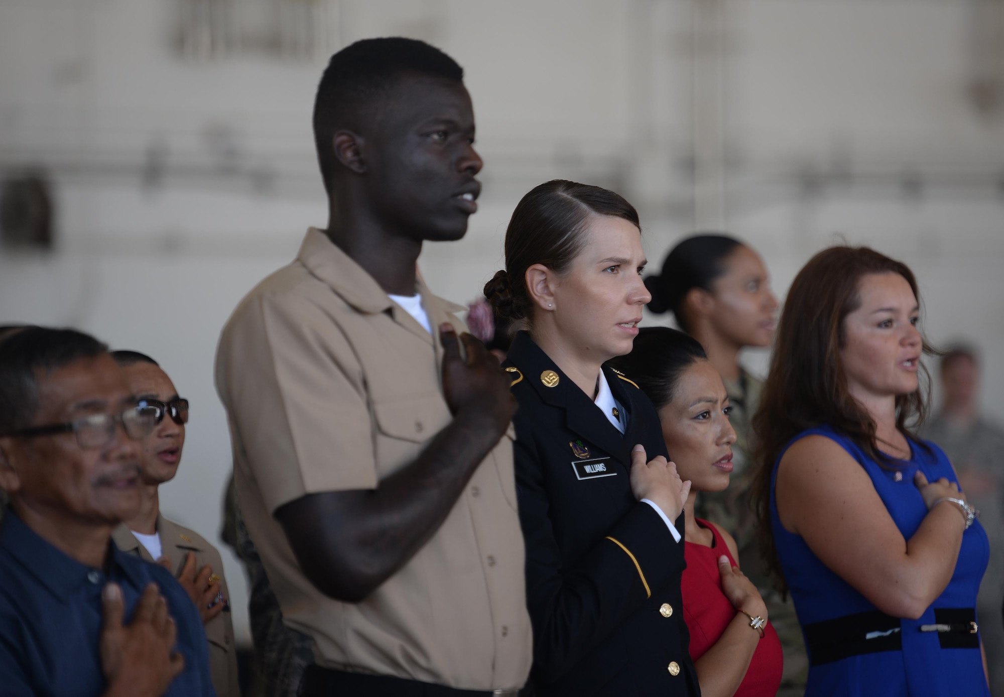 Newly naturalized U.S. citizens place their right hands over their heart as they recite the Pledge of Allegiance during a naturalization ceremony Nov. 23, 2016, on Andersen Air Force Base, Guam. A naturalization ceremony is the culmination serves of extensive application procedures, background investigations and successful completion of a citizenship test. (U.S. Air Force photo/Staff Sgt. Benjamin Gonsier)