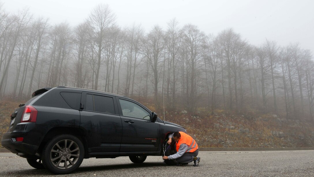 An Airman places snow chains on a tire at Piancavallo, Italy on Nov. 22, 2016. Before driving, winter travelers are encouraged to check weather conditions and ensure tires are in good condition. (U.S. Air Force photo by Senior Airman Cary Smith)