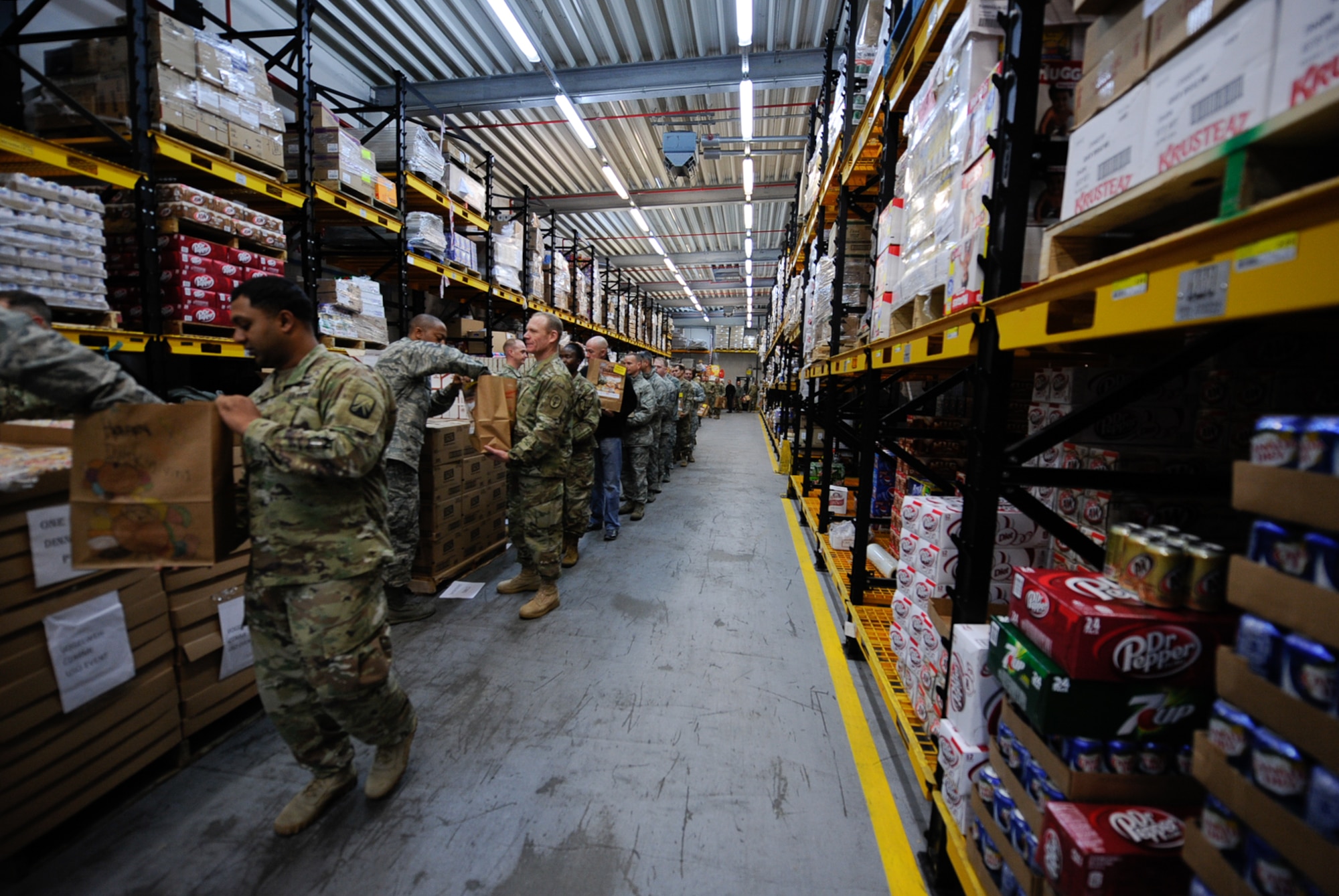 Airmen and Soldiers line up to fill bags with food and supplies at the Thanks for Thanksgiving event at Vogelweh Air Base. Germany, Nov. 19, 2016. Kaiserslautern Military Community leaders banded together to support junior enlisted service members by providing them with all the fixings for a traditional Thanksgiving meal (U.S. Air Force photo by Airman 1st Class Savannah L. Waters)