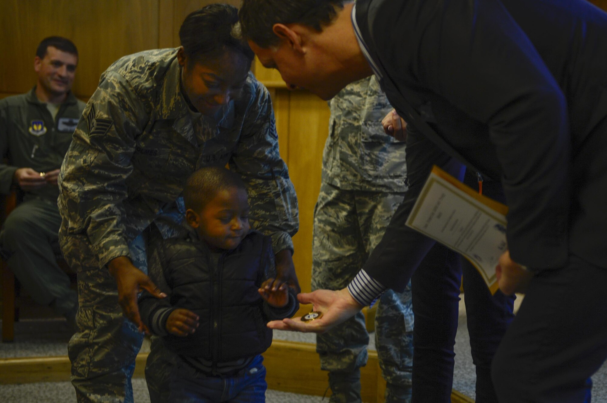 Tom Burkett, Troop Rewards director, coins the son of a 48th Fighter Wing Airman, Nov. 21, at Royal Air Force Lakenheath, England. Troop Rewards travels to Europe every other year and gives 100 families a year a free vacation. This year, 10 families on RAF Lakenheath received free vacations. (U.S. Air Force photo/Senior Airman Malcolm Mayfield)